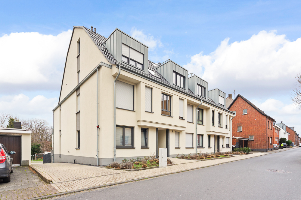 Modernes, helles Wohngebäude mit mehreren Etagen an einer ruhigen Wohnstraße.