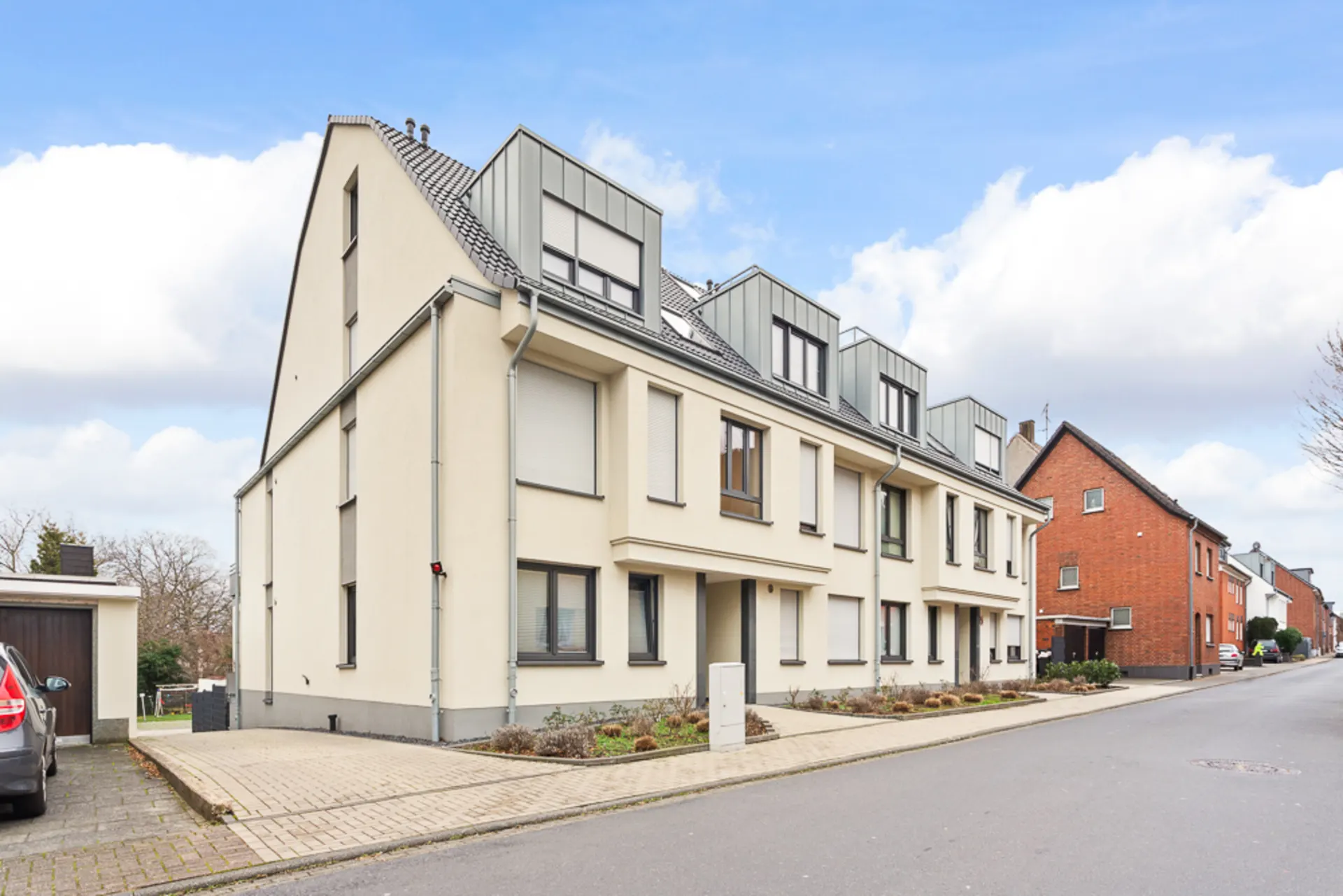 Modernes, helles Wohngebäude mit mehreren Etagen an einer ruhigen Wohnstraße.