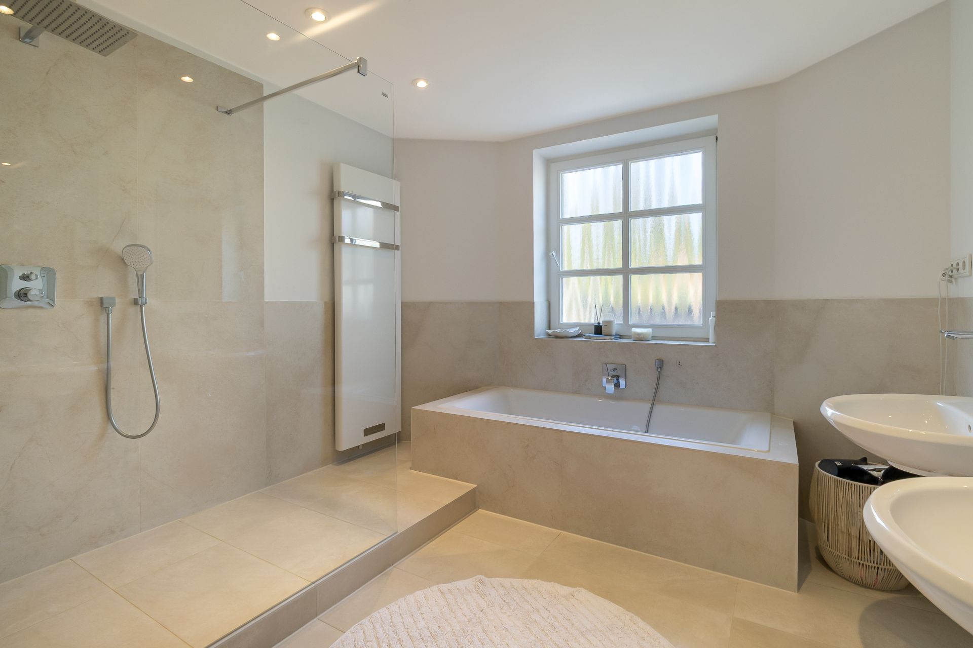 Modernes Badezimmer mit begehbarer Dusche, Badewanne, großem Fenster und Doppelwaschbecken.