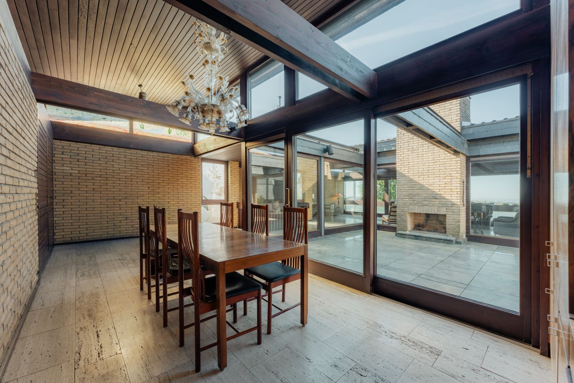 Esszimmer mit Holztisch, sechs Stühlen und großen Fenstern zur Terrasse.