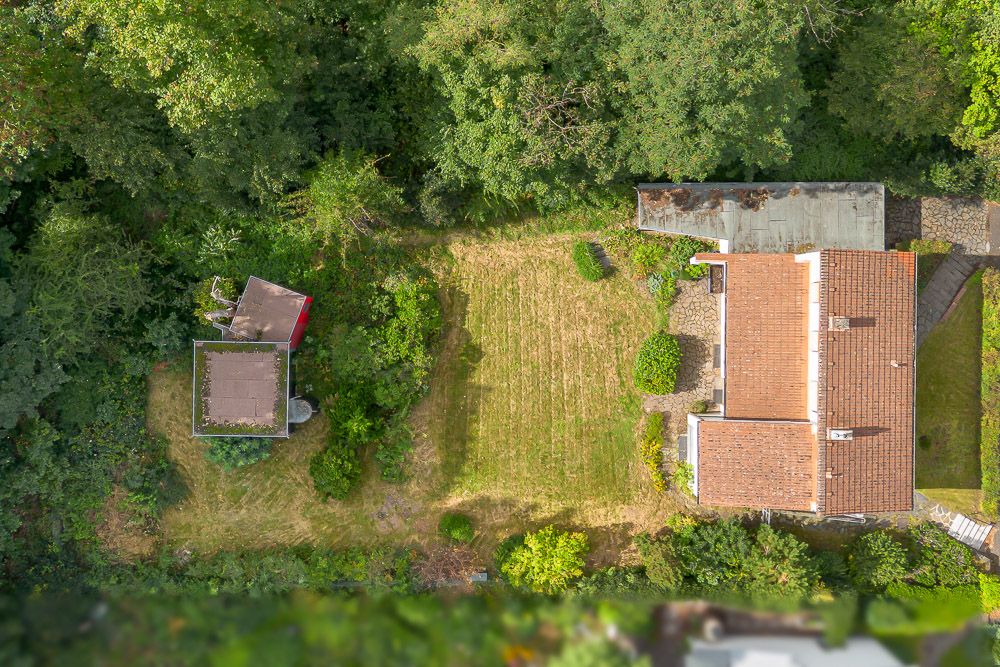 Luftaufnahme eines Hauses mit Garten und Nebengebäude, umgeben von Bäumen.