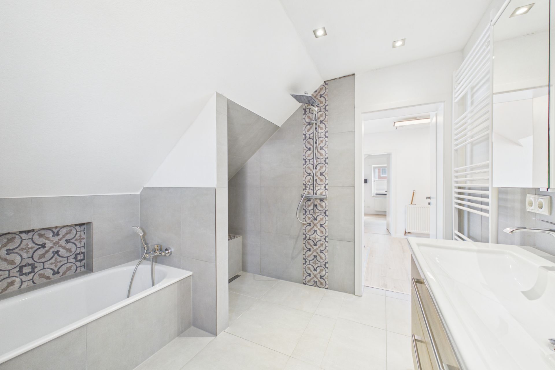 Modernes Badezimmer mit Badewanne, Dusche, Waschbecken und dekorativen Fliesen.