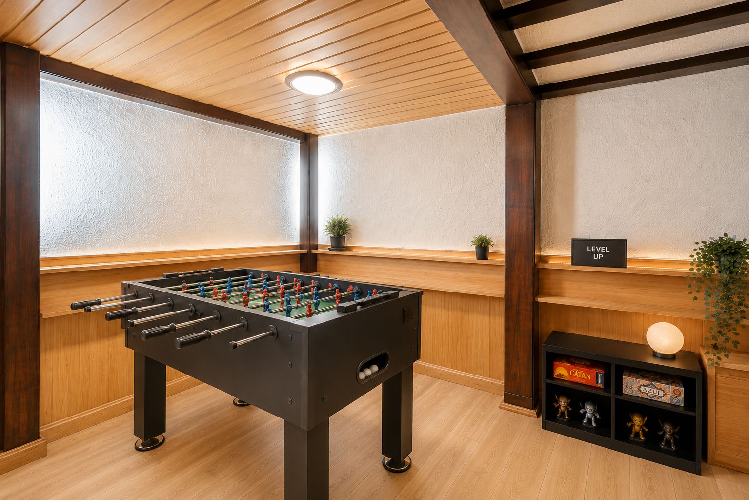 Raum mit Kickertisch, Regal mit Brettspielen und Dekoration, Holzdecke und Topfpflanzen.