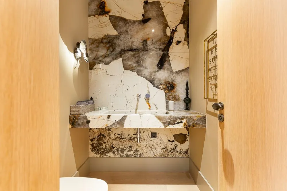 Modernes Badezimmer mit großem Marmorwaschbecken und Marmorwand, offene Holztür.