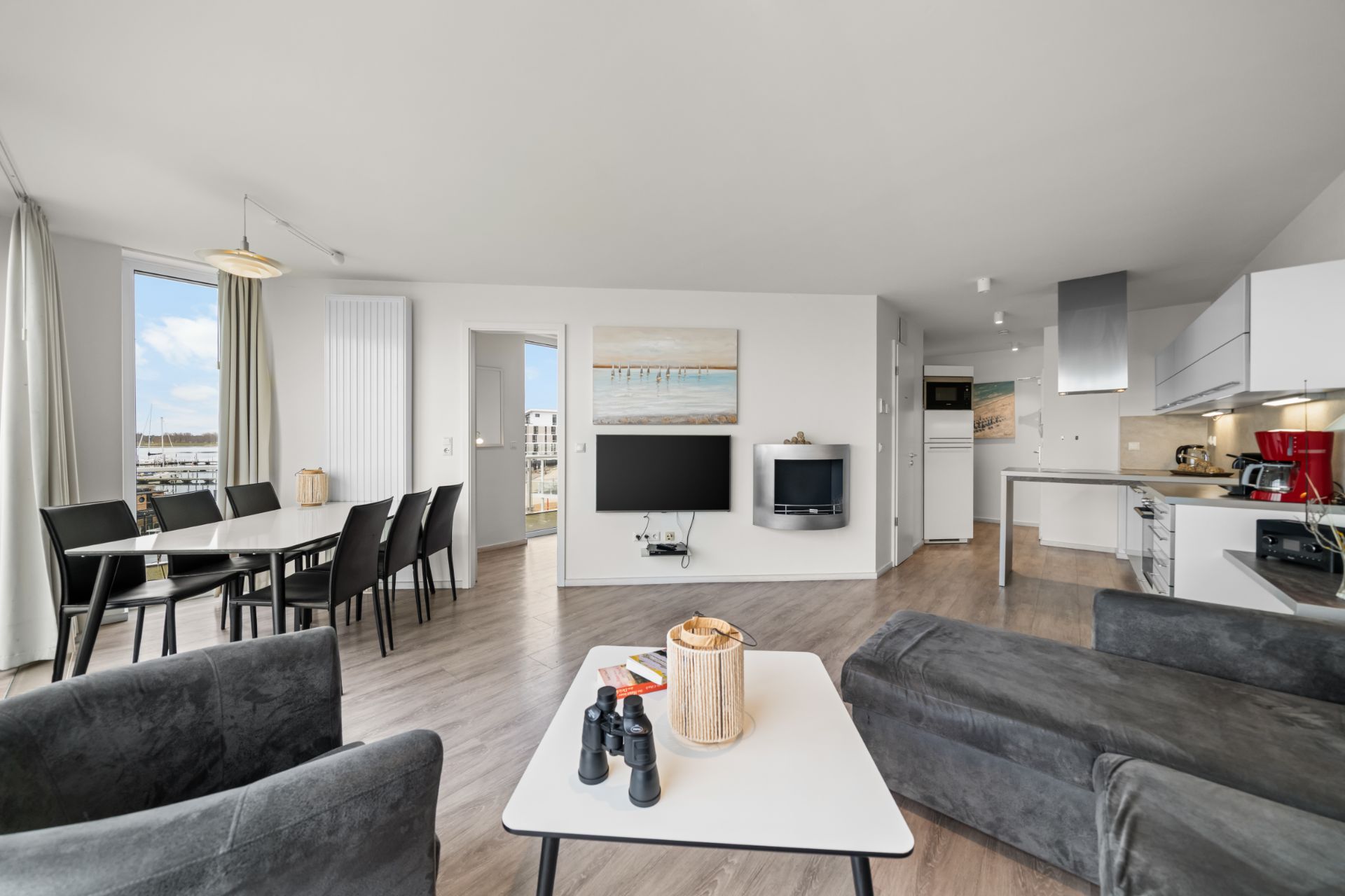 Helles Wohnzimmer mit Esstisch, offener Küche und moderner Einrichtung.