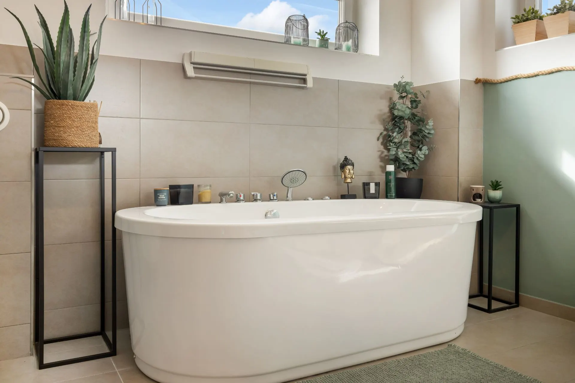 Modernes Badezimmer mit freistehender Badewanne, Pflanzen und großen Fenstern.