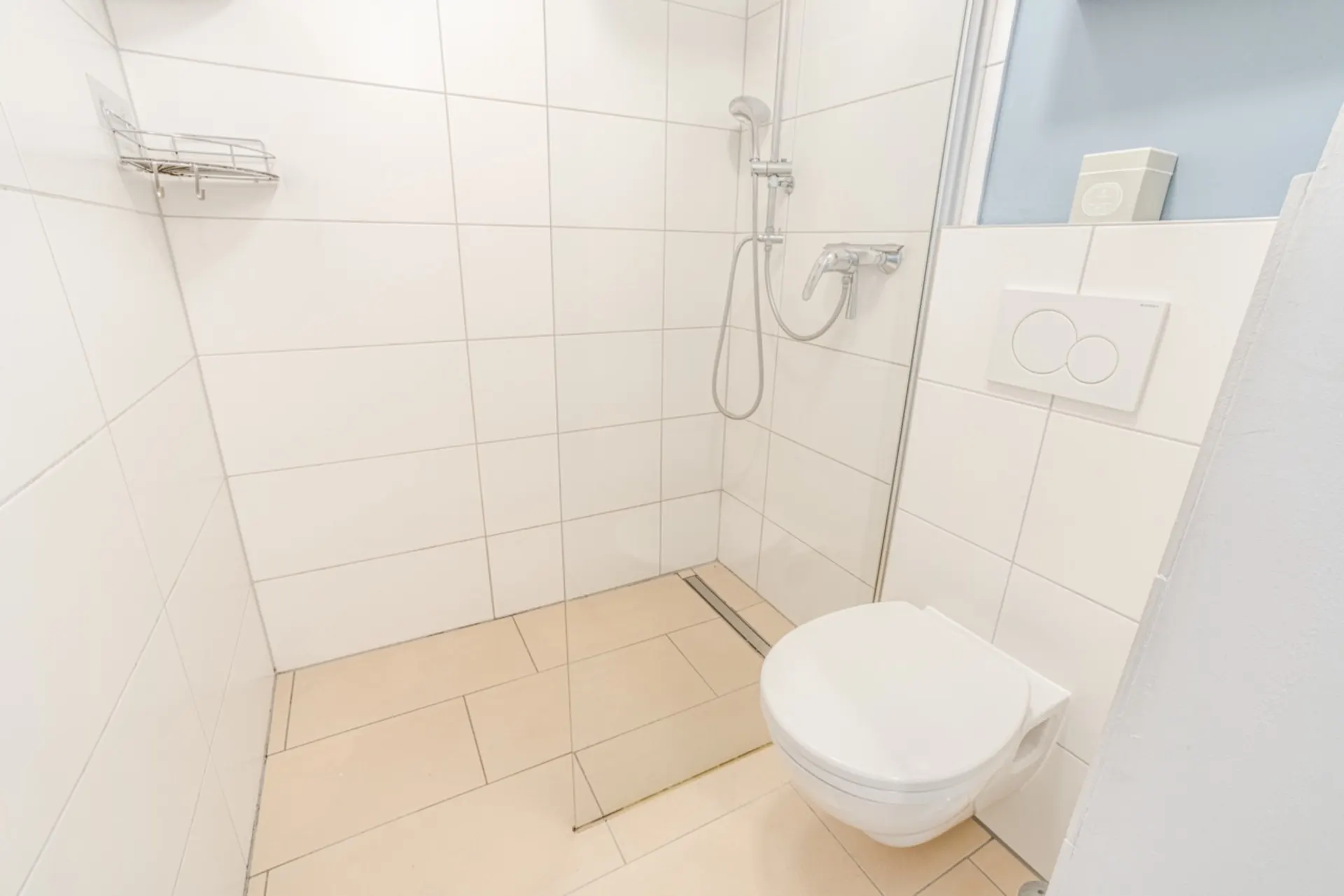 Modernes Bad mit bodengleicher Dusche, Glasabtrennung und Wand-WC.