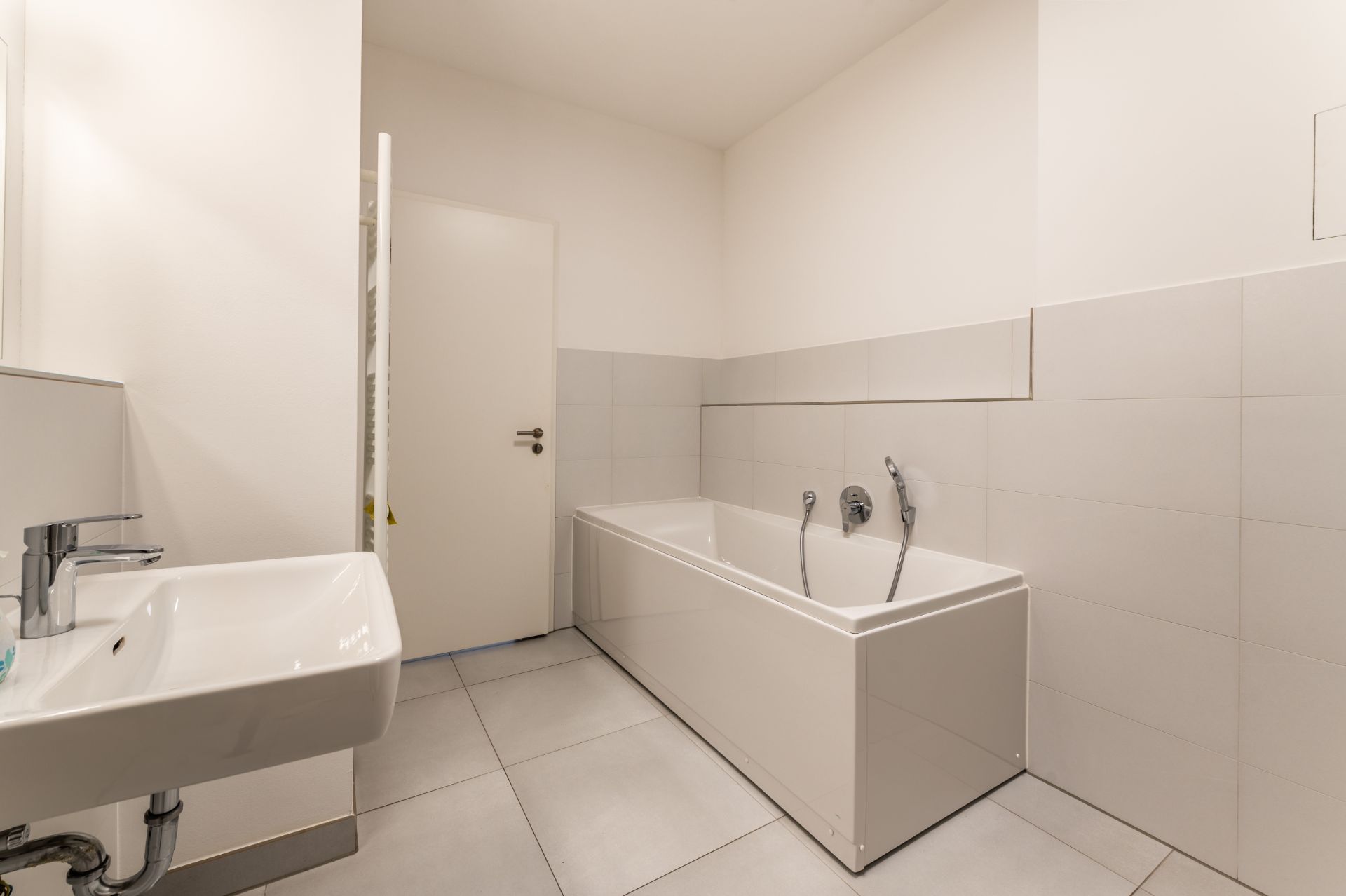 Modernes Badezimmer mit Badewanne, Waschbecken und hellen Fliesen.