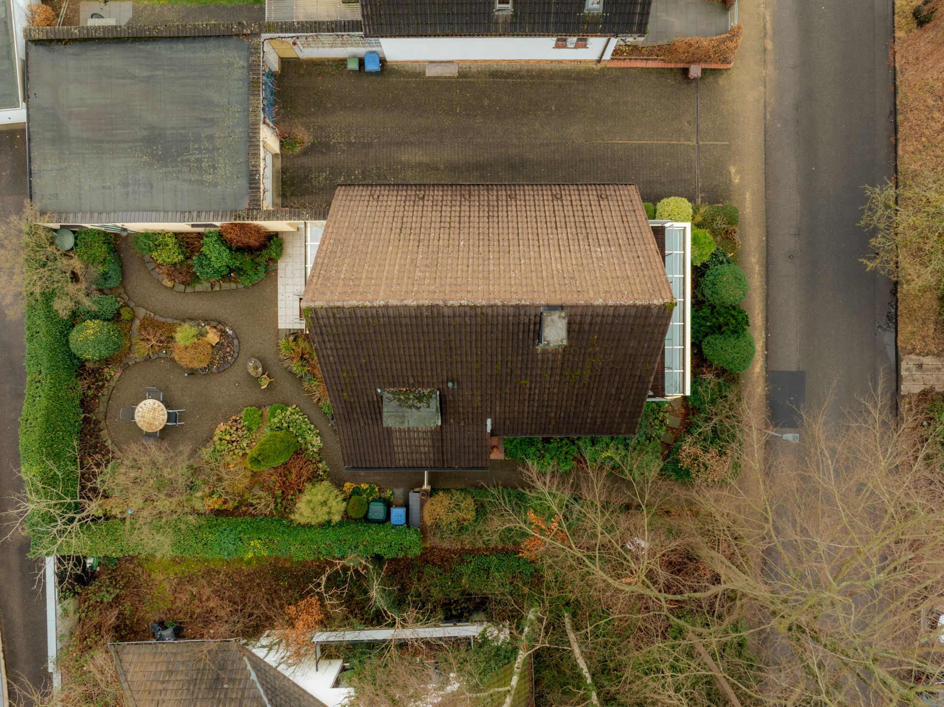 Luftaufnahme eines Hauses mit Garten, Gehweg und Gartenmöbeln im Vorgarten.