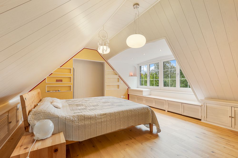 Helles Schlafzimmer im Dachgeschoss mit Holzboden, Doppelbett und großem Fenster.