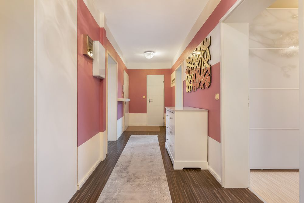 Flur mit rosa und weißen Wänden, Teppichläufer und Kommode, moderne Wanddekoration.