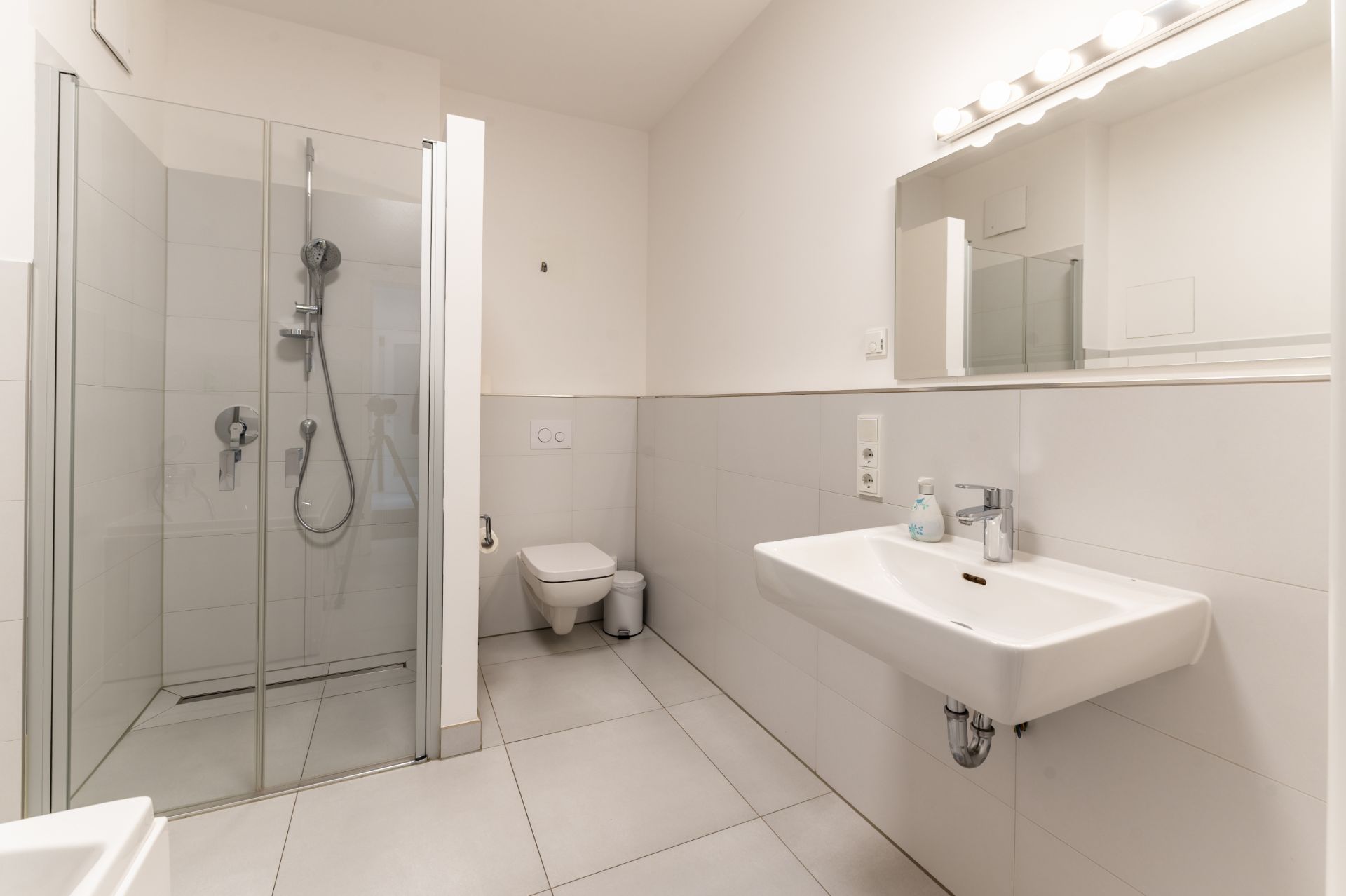 Modernes Badezimmer mit Dusche, Waschbecken, Spiegel und WC.