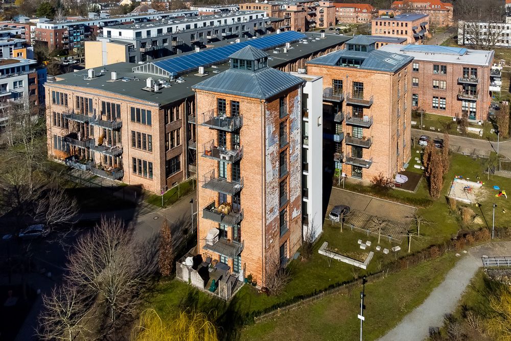 Mehrstöckiges Wohngebäude aus Backstein mit Balkonen, umgeben von Grünflächen.