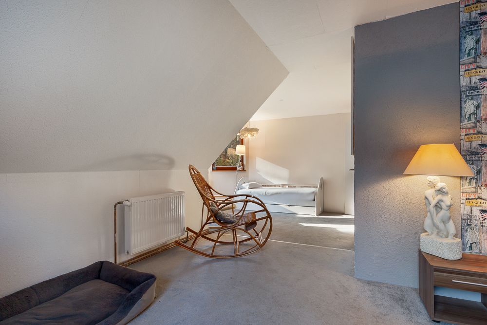 Raum mit Schaukelstuhl, Hundebett, Lampe auf Tisch und Bett im Hintergrund.