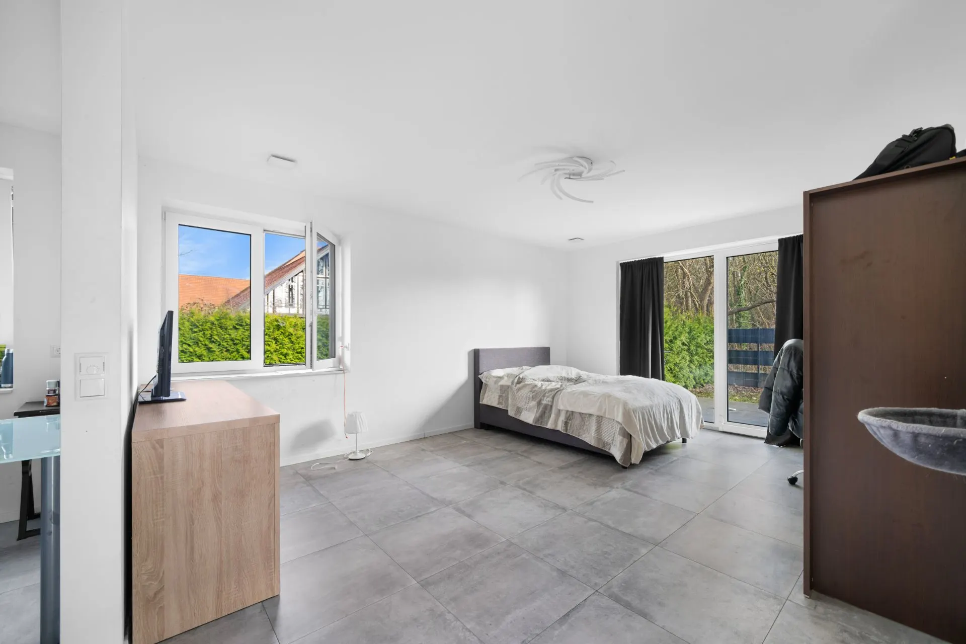 Helles Schlafzimmer mit großem Fenster, Doppelbett, Fliesenboden und Zugang zur Terrasse.