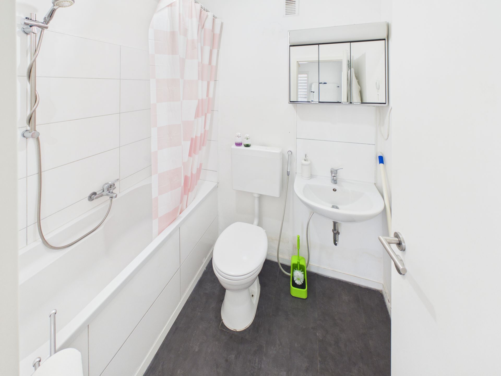 Helles Badezimmer mit Badewanne, Toilette, Waschbecken und Spiegelschrank.