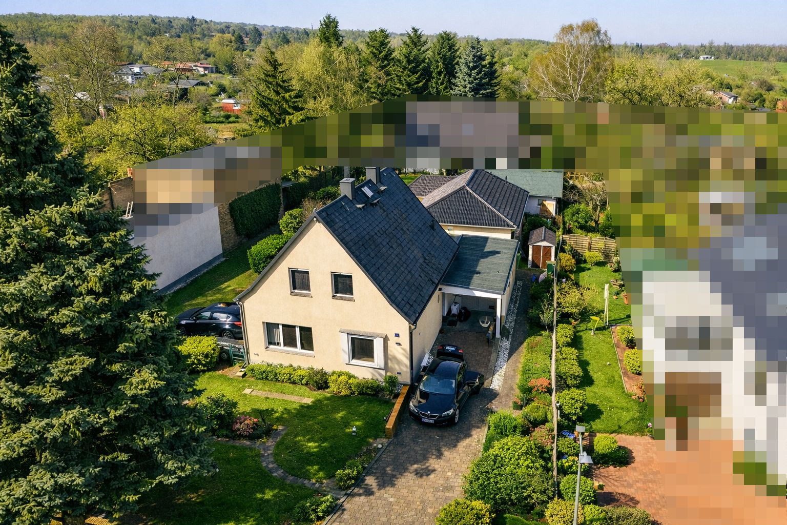 Luftaufnahme eines Einfamilienhauses mit Garten, Zufahrt und parkendem Auto.