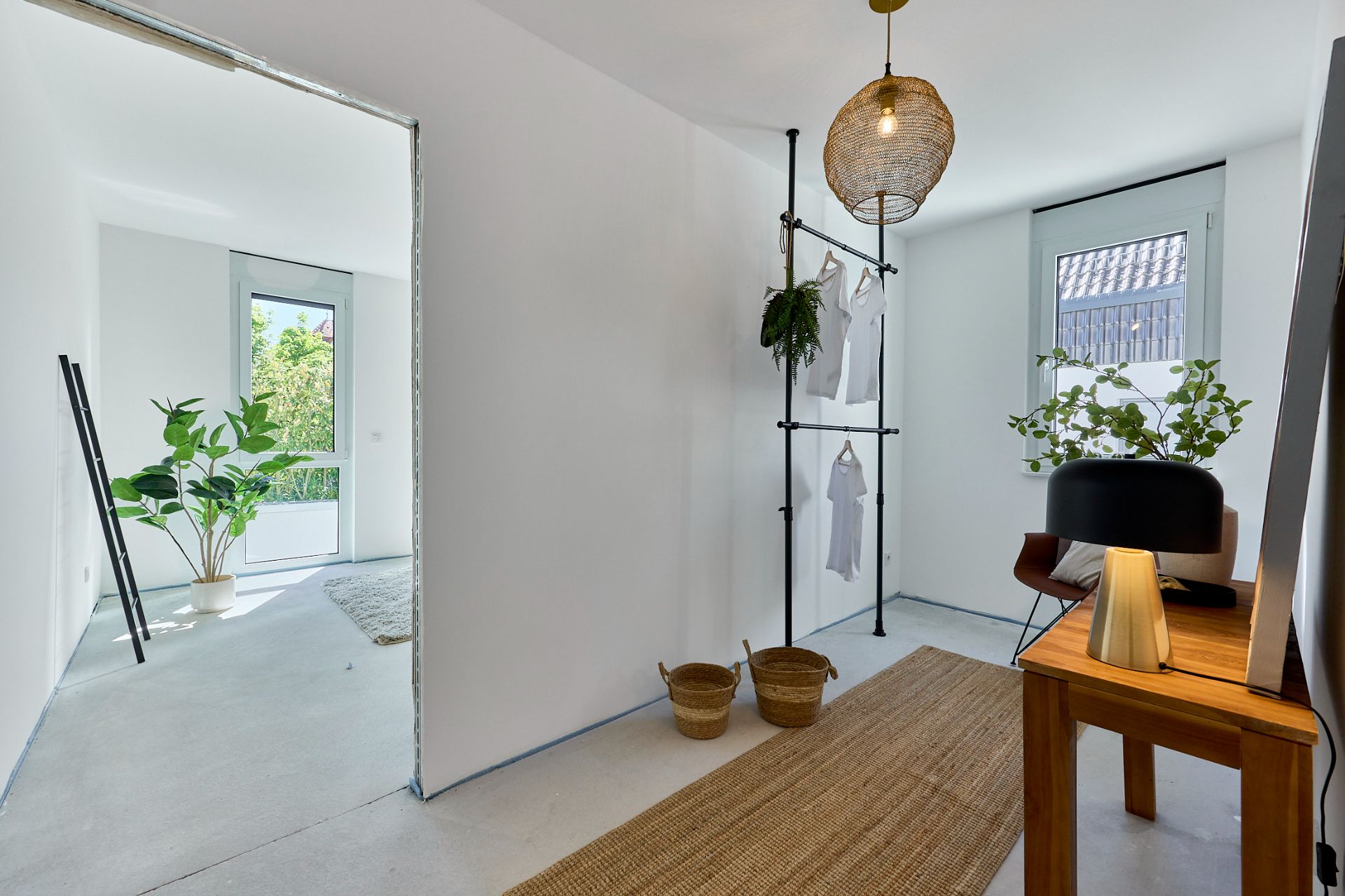 Heller Flur mit Teppich, Holztisch, Pflanzen und Fenster, angrenzend an ein weiteres Zimmer.