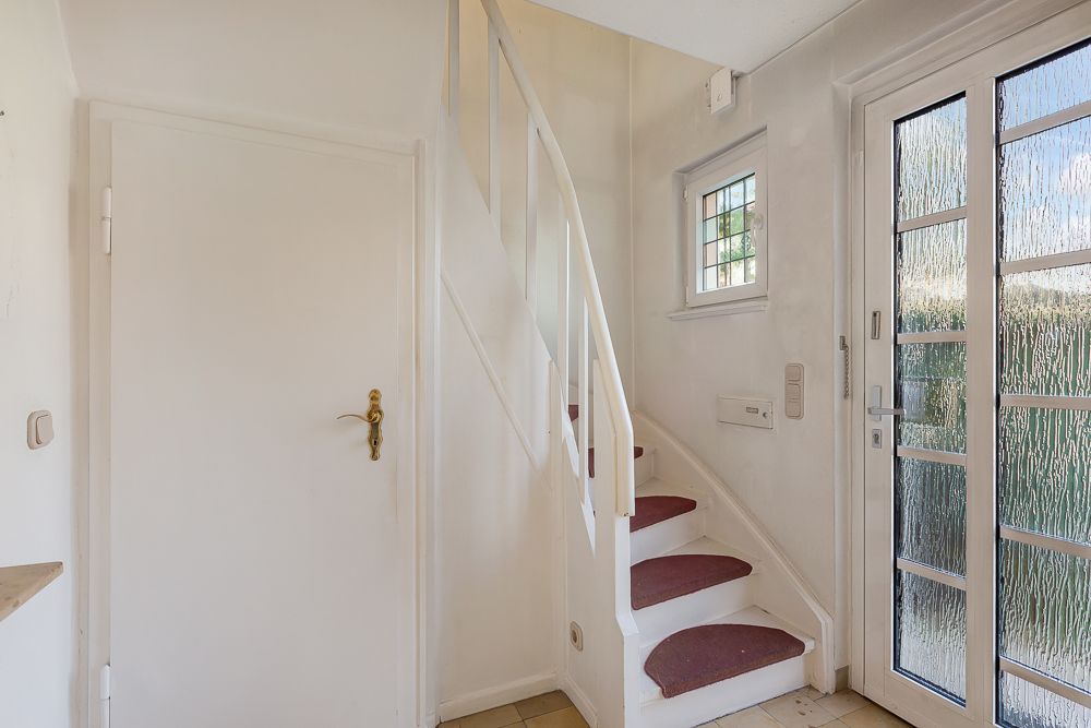 Eingangsbereich mit weißer Tür, Fenster, Treppe und Glastür.