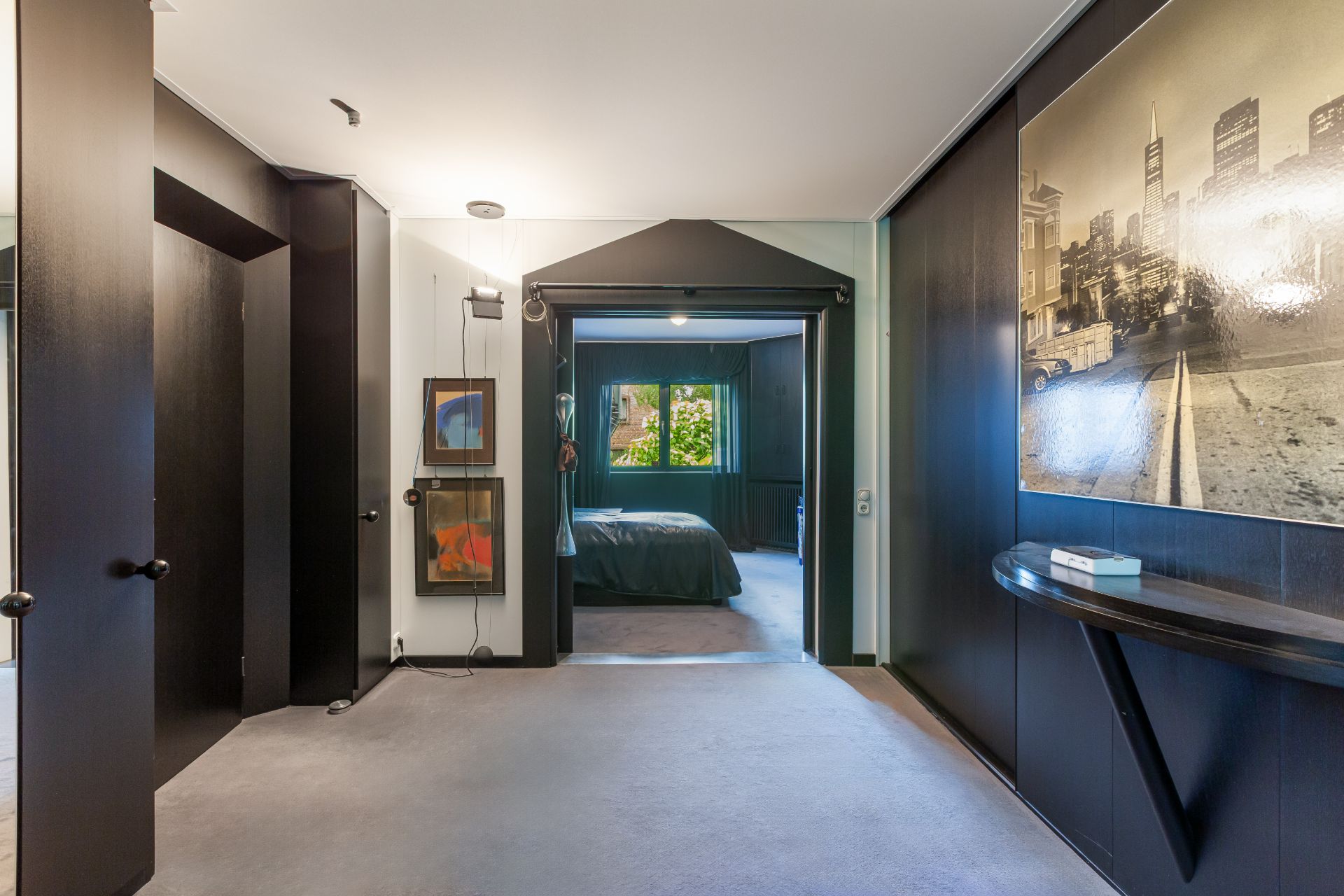 Flur mit offener Tür zum Schlafzimmer, Wandbildern und großem Foto an der rechten Wand.