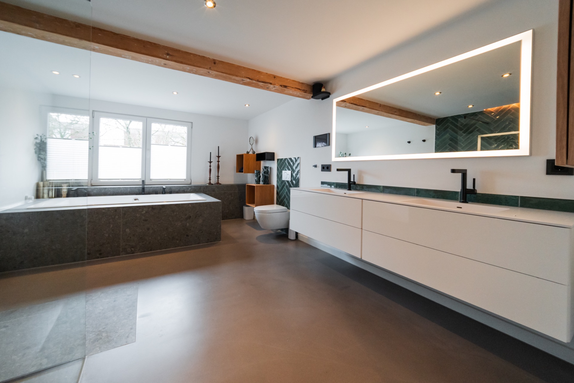 Modernes Badezimmer mit großer Badewanne, Doppelwaschbecken und beleuchtetem Spiegel.