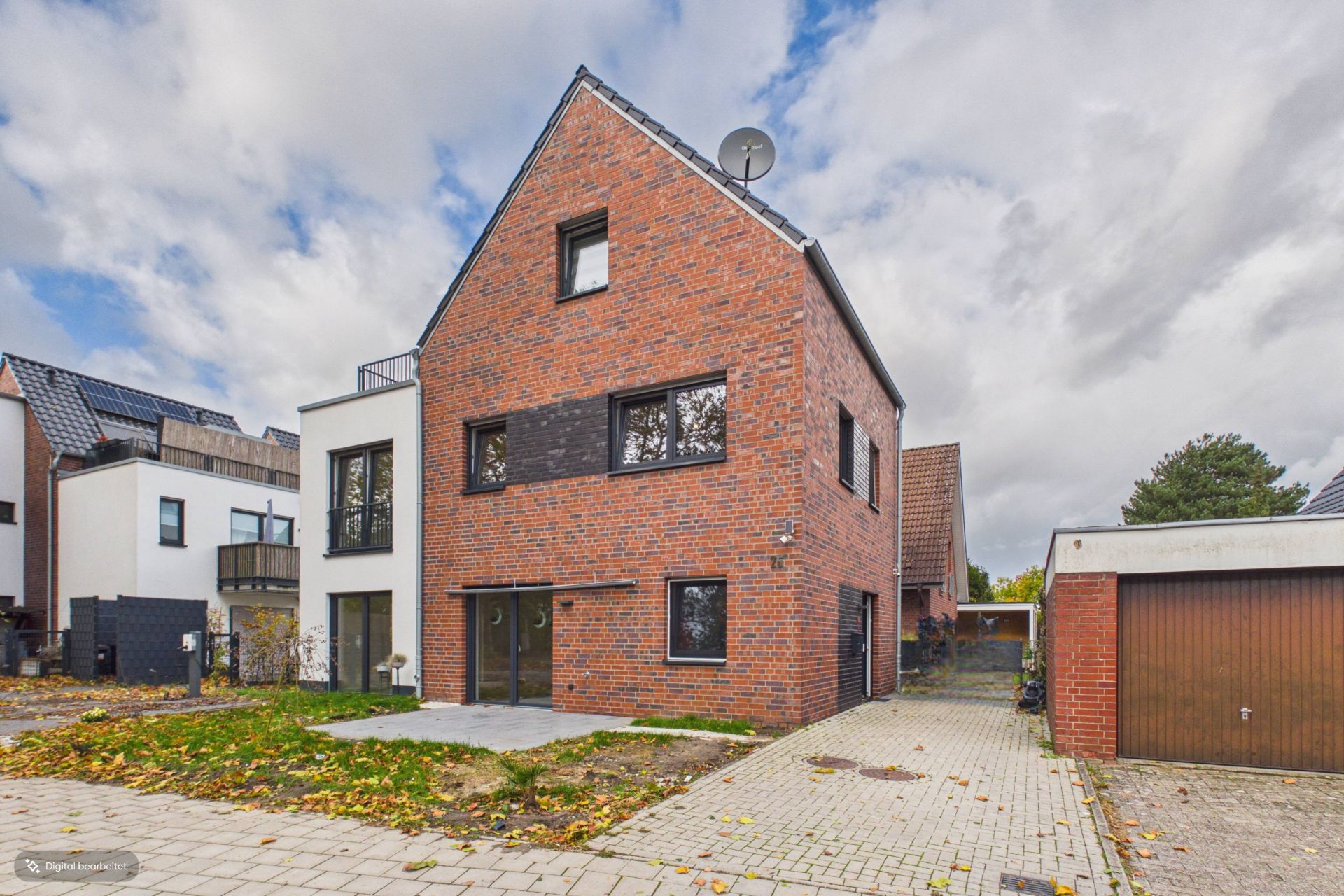 Modernes zweistöckiges Backsteinhaus mit Einfahrt und Garage, umgeben von anderen Wohnhäusern.