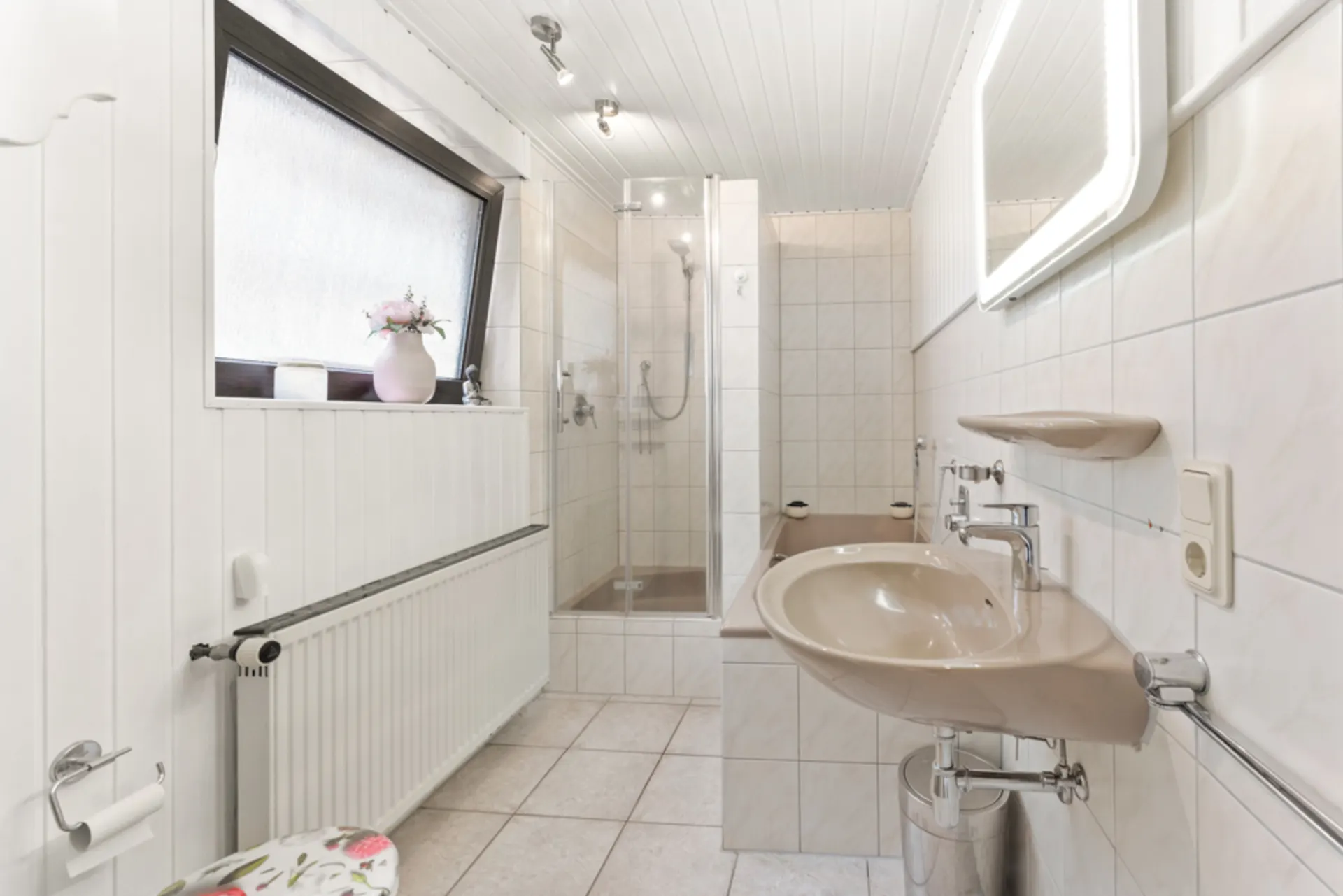 Helles Badezimmer mit Waschbecken, Dusche, Badewanne und großem Fenster.