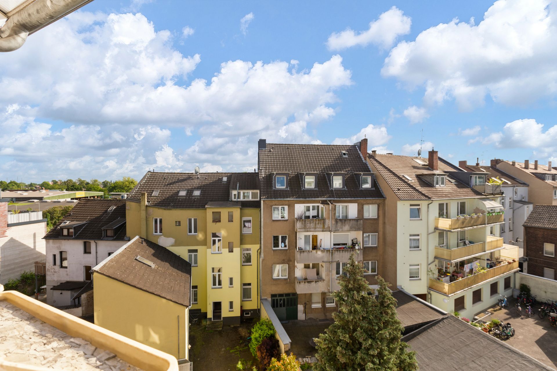 Blick auf mehrere Wohnhäuser mit Balkonen und leicht bewölktem Himmel.