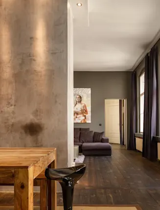 Modernes Wohnzimmer mit Holztisch, grauem Sofa, großen Fenstern und Stehlampe.