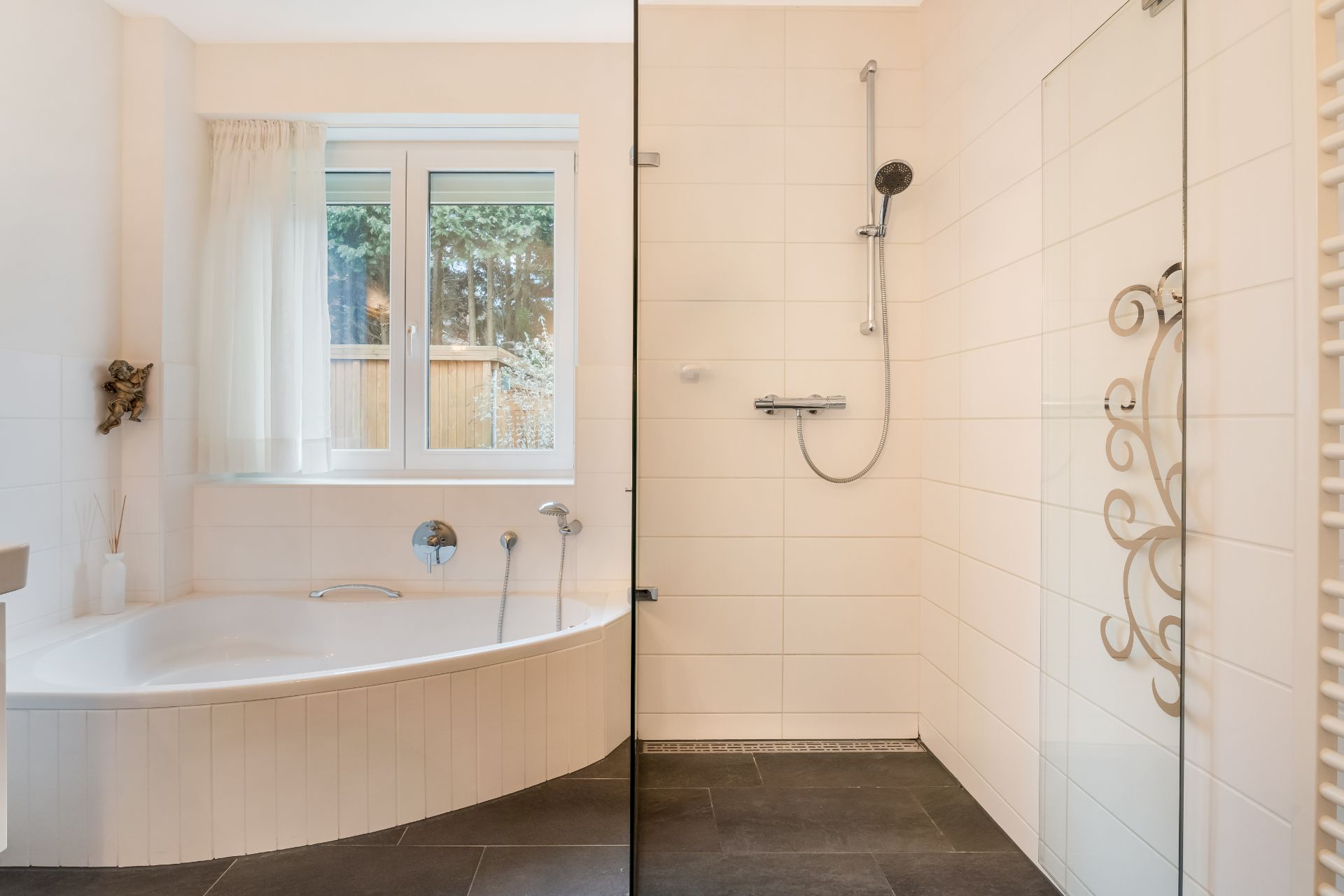 Modernes Badezimmer mit Eckbadewanne, Dusche mit Glaswand und Fenster mit Vorhang.