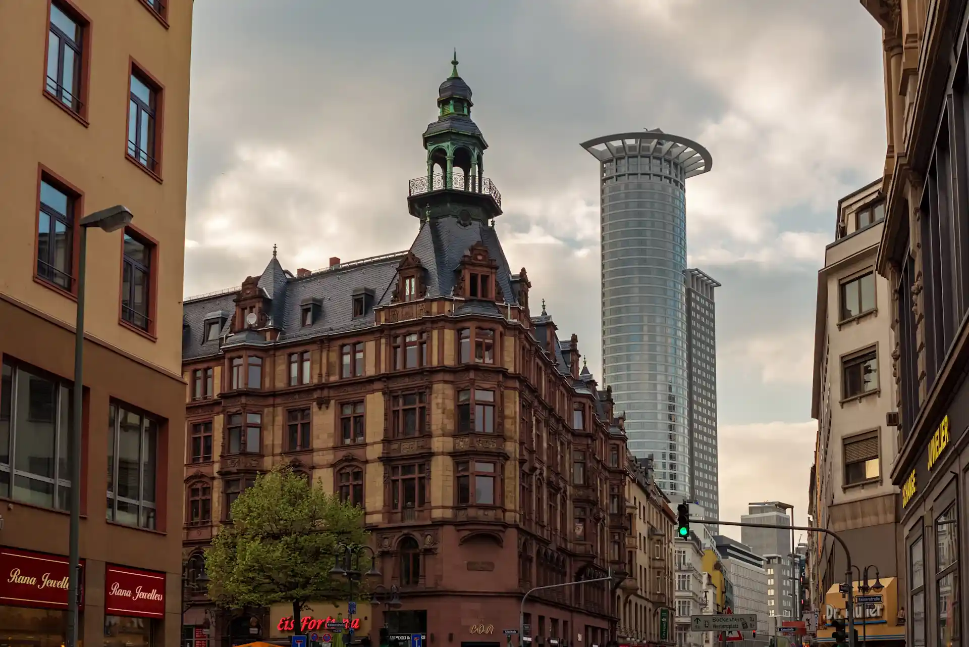Mehrstöckiges historisches Wohngebäude mit Turm und modernen Hochhäusern im Hintergrund.