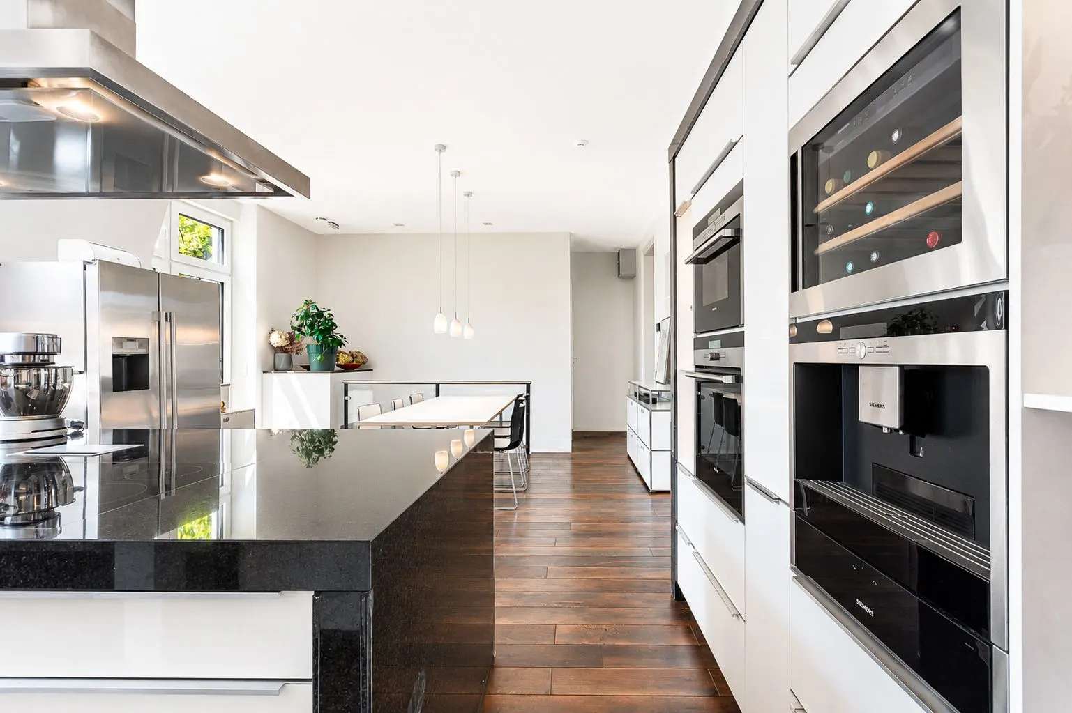Moderne Küche mit dunkler Arbeitsplatte, Einbaugeräten und Holzboden.