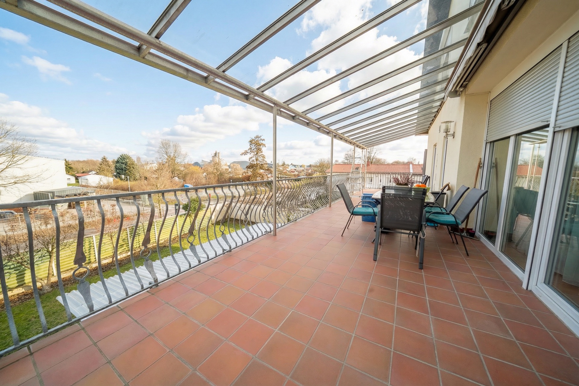 Überdachte Terrasse mit Esstisch und Stühlen, Blick auf Garten und Bäume.