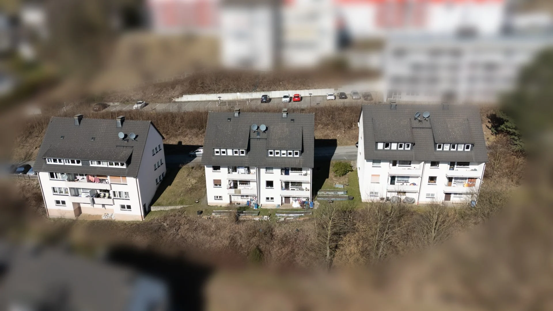 Drei weiße Wohnhäuser mit Gärten sind nebeneinander aus der Vogelperspektive zu sehen.