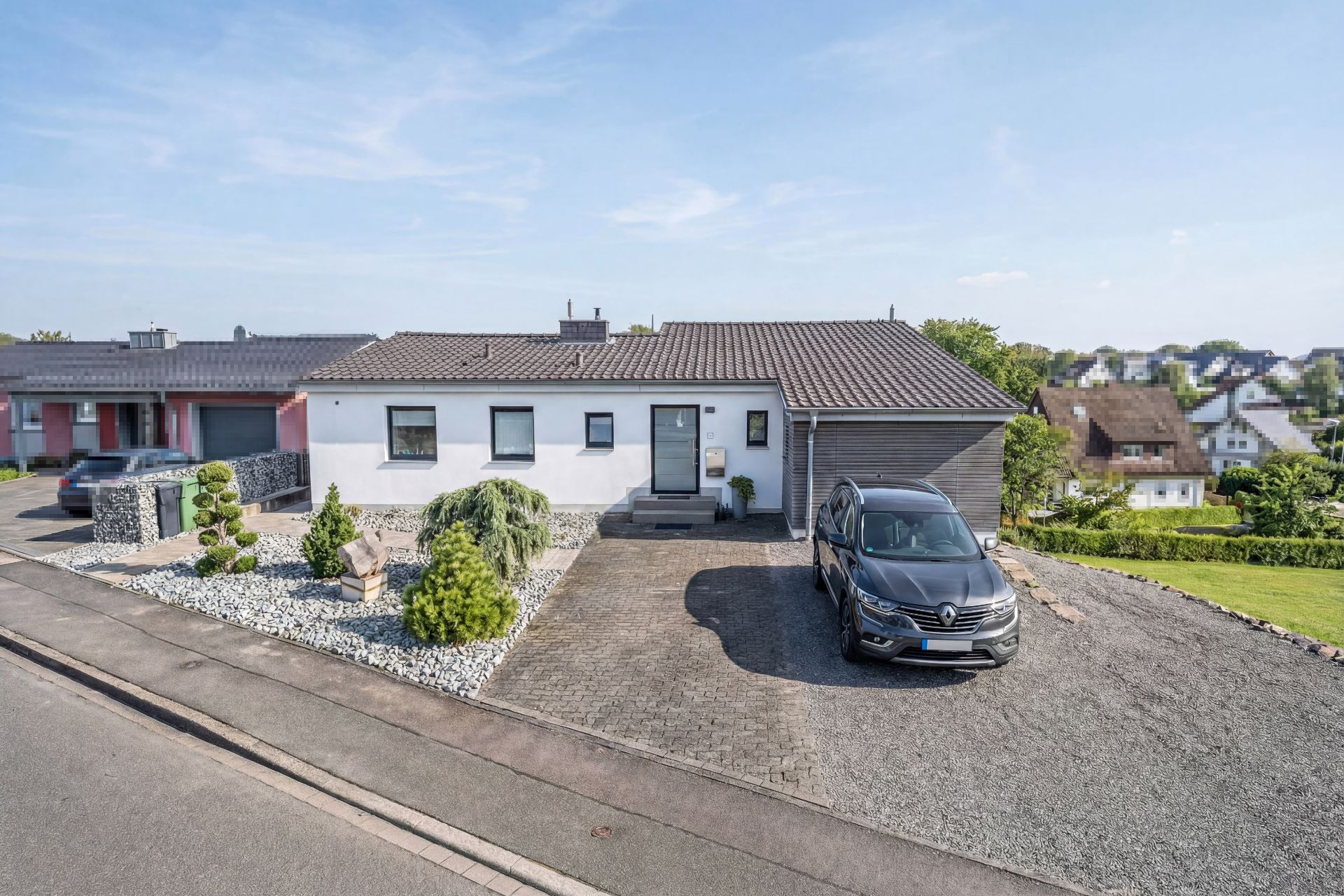 Einfamilienhaus mit grauem Dach, Garage, geparktem Auto und gepflegtem Vorgarten.