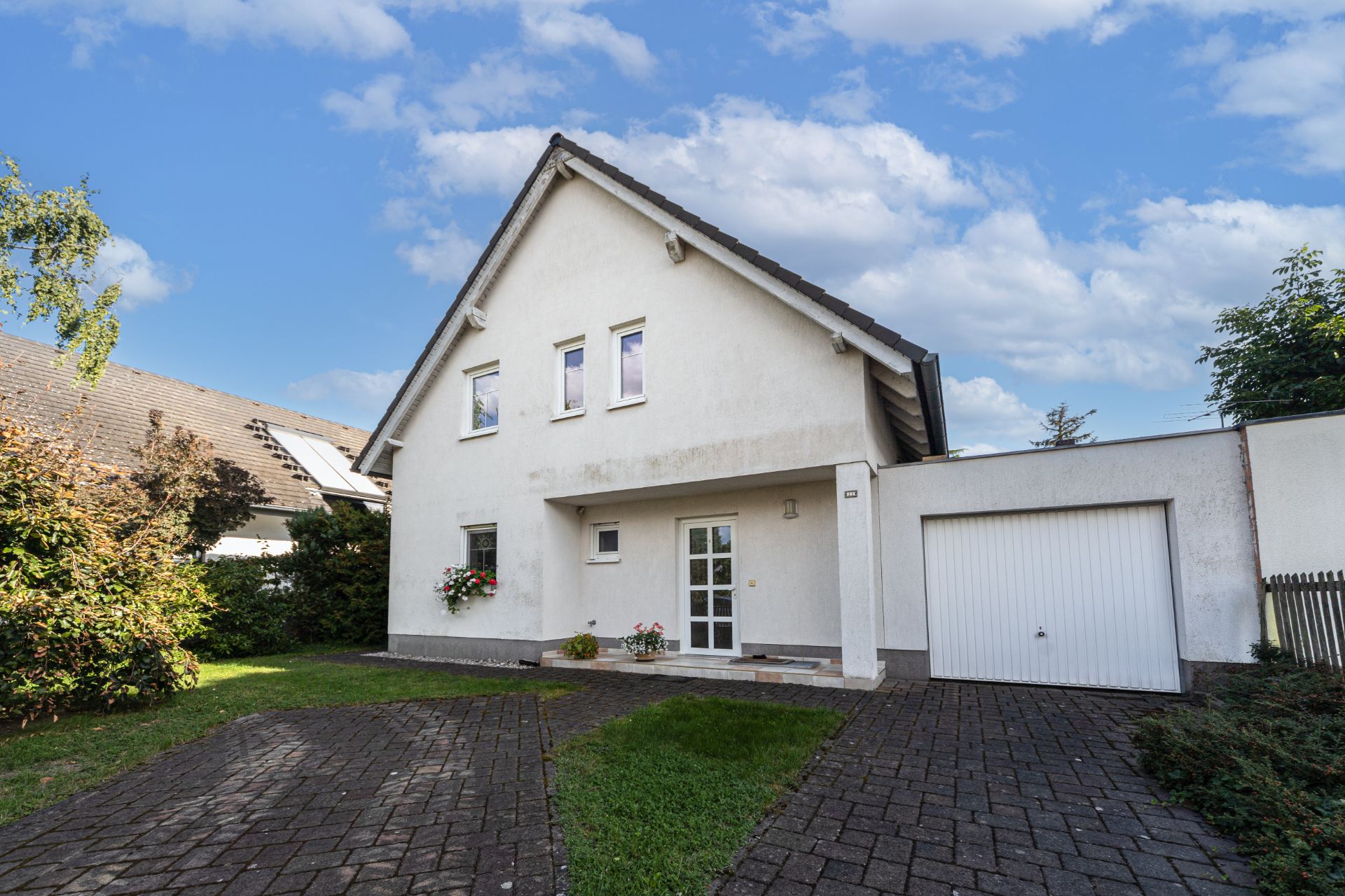 Zweistöckiges Einfamilienhaus mit Giebeldach, Garage und gepflasterter Einfahrt.