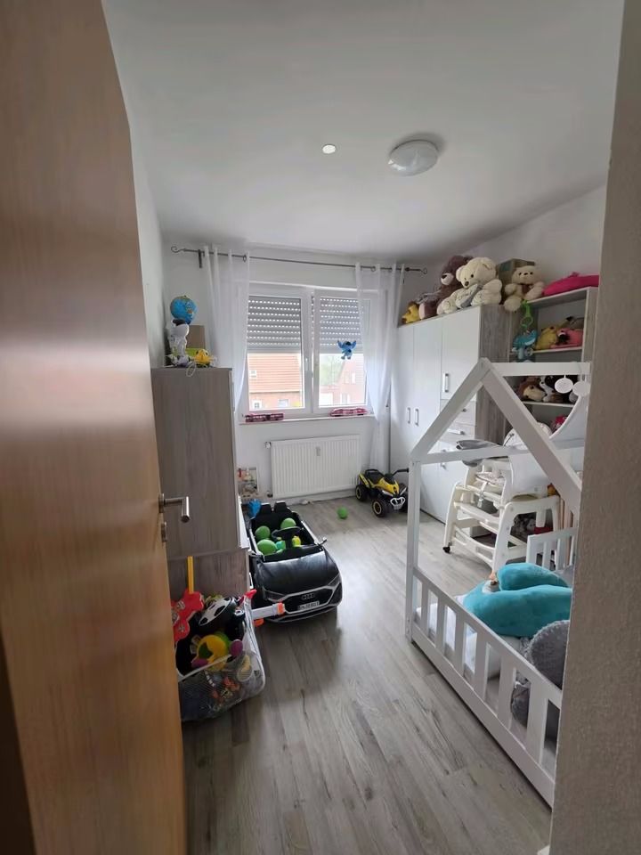 Kinderzimmer mit Spielzeugautos, Kuscheltieren und einem weißen Kinderbett.