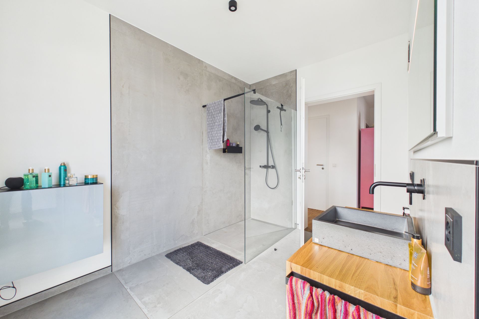 Modernes Badezimmer mit bodengleicher Dusche, Waschbecken und Handtuch.