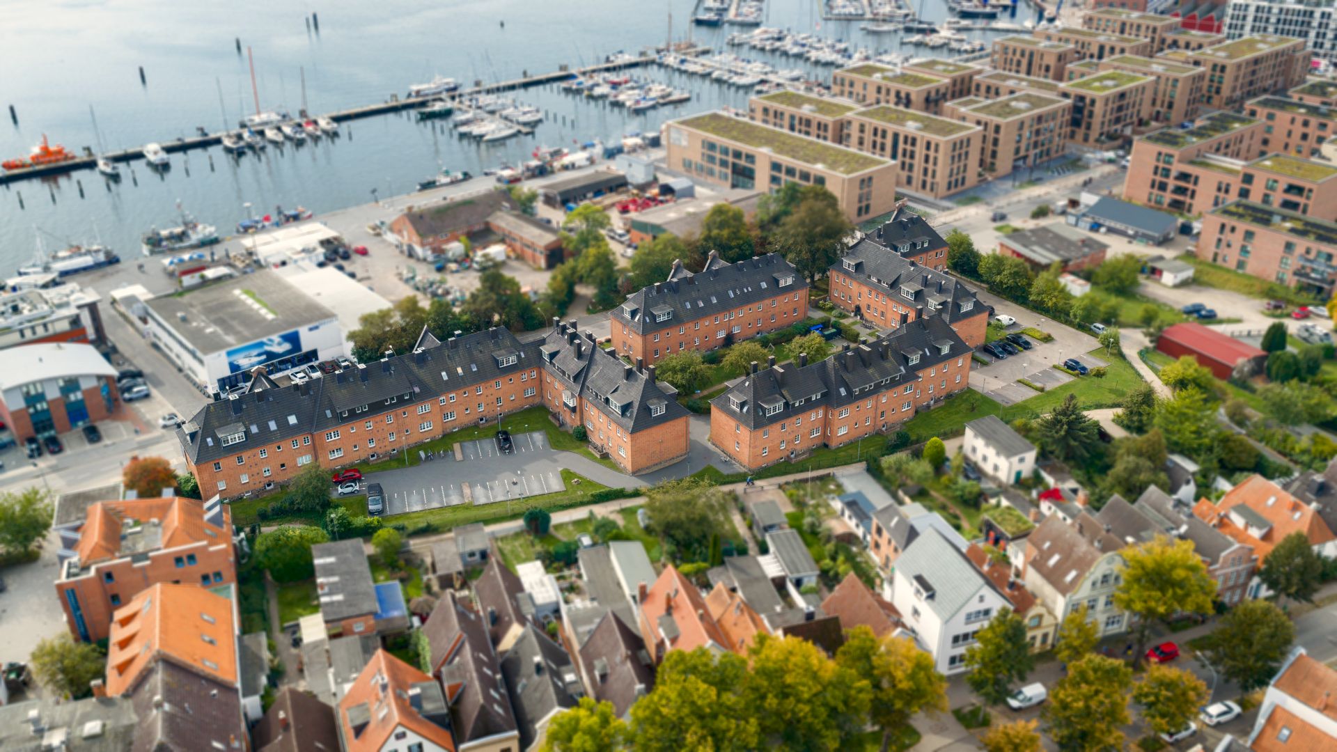 Luftaufnahme mehrerer Wohngebäude in der Nähe eines Hafens mit vielen Booten.