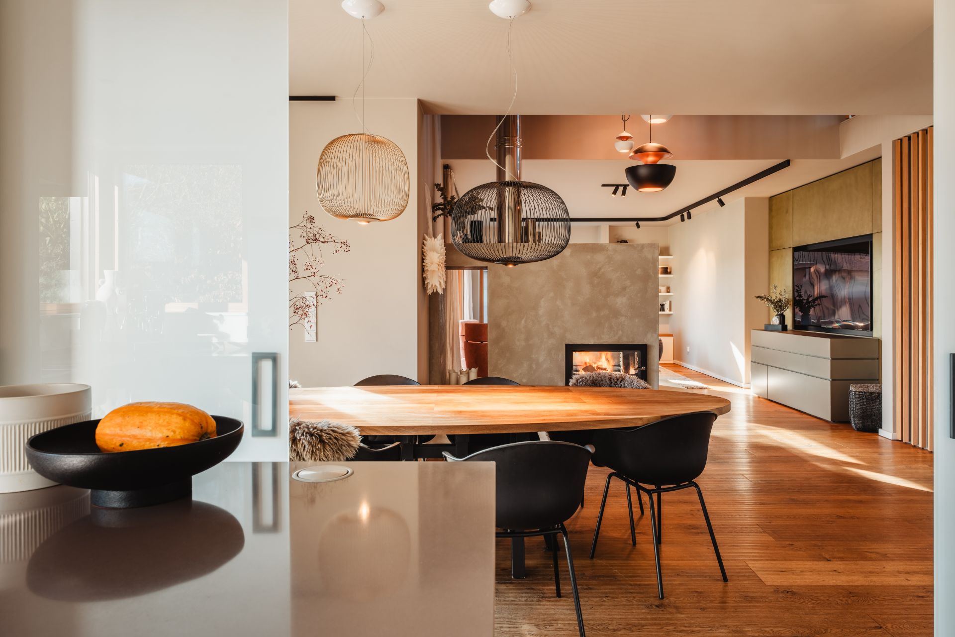 Modernes Wohnzimmer mit Holzboden, Esstisch, Kamin und dekorativen Lampen.