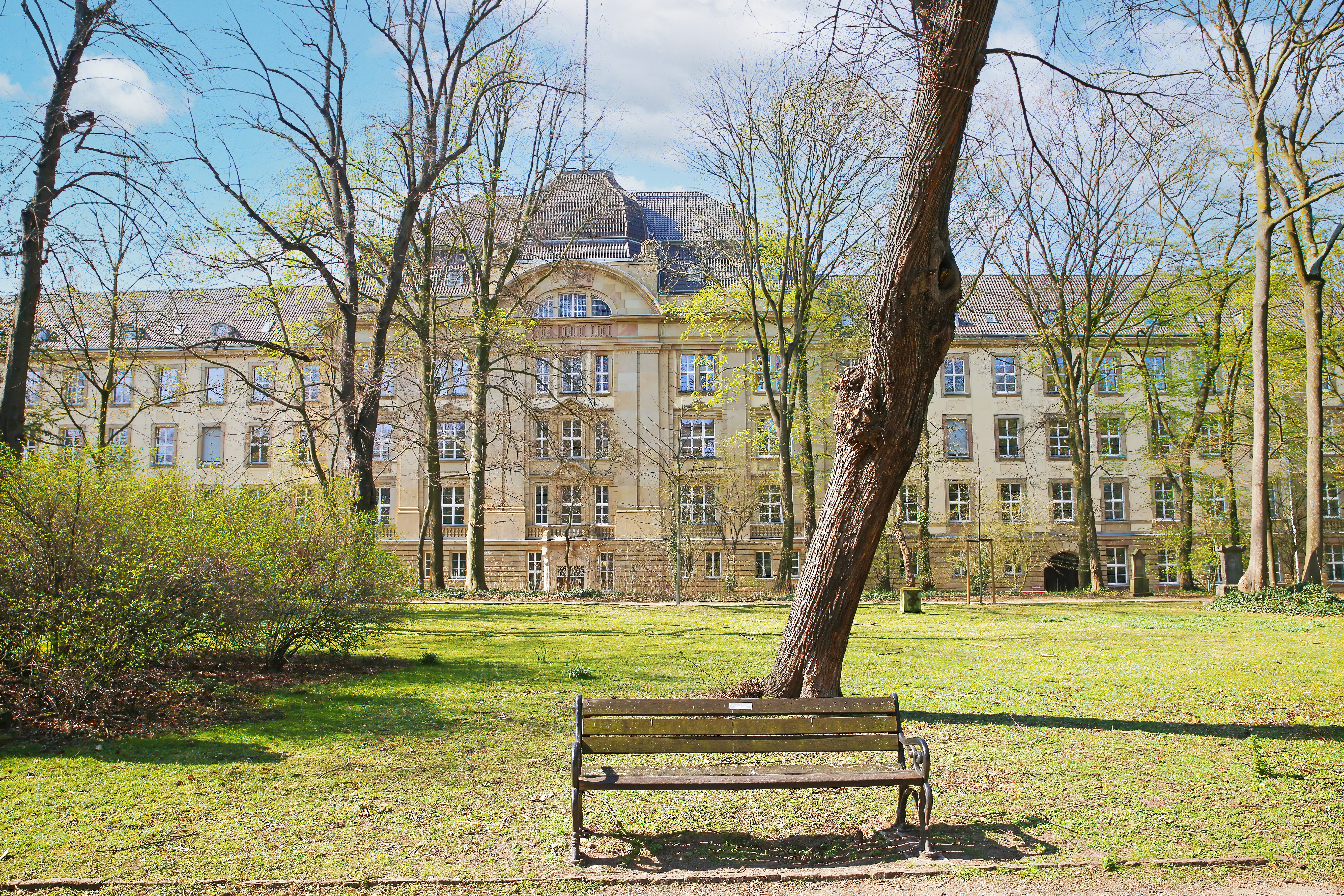 Luftaufnahme einer Stadt mit großen Gebäuden, vielen Bäumen und Straßen im Vordergrund.