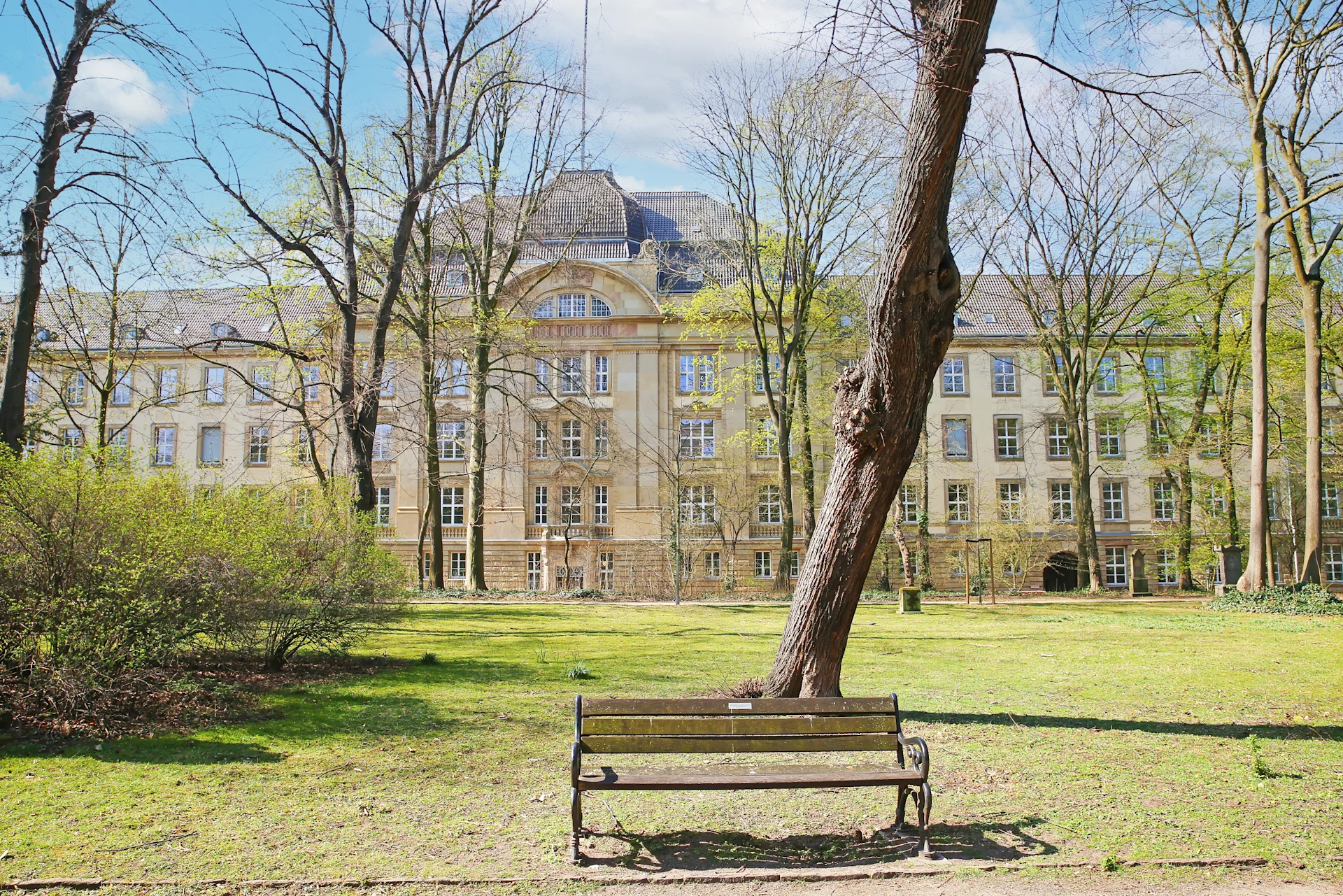 Luftaufnahme einer Stadt mit großen Gebäuden, vielen Bäumen und Straßen im Vordergrund.