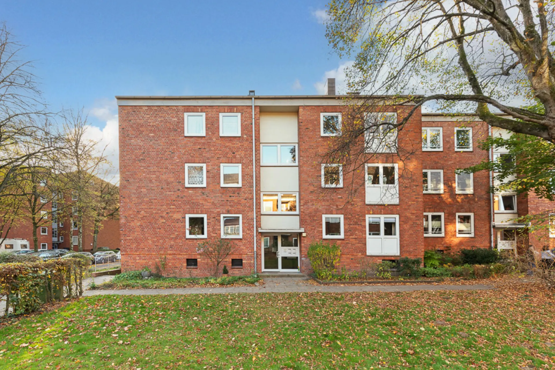 Dreistöckiges Wohnhaus aus rotem Backstein mit mehreren Fenstern und einem Eingangsbereich.