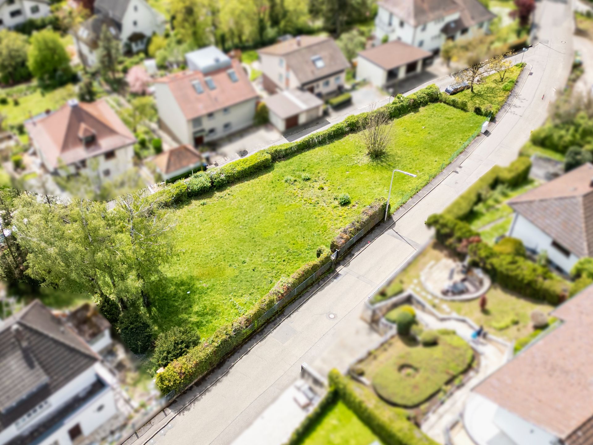 Luftaufnahme eines rechteckigen, eingezäunten Grundstücks mit Wiese in einer Wohngegend.
