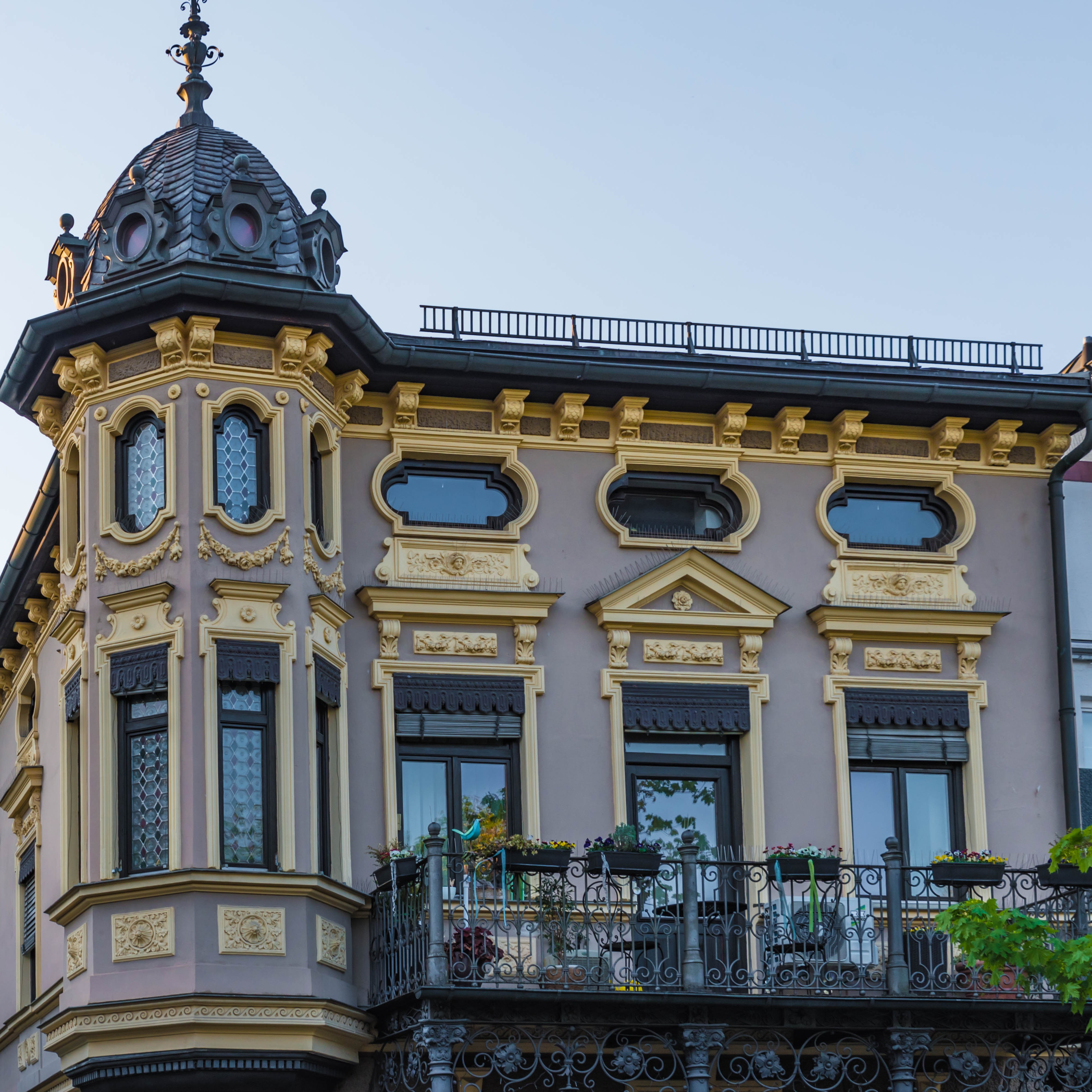 Historisches Wohnhaus mit reich verzierten Fassadendetails und Balkon, Ecke des Gebäudes mit Kuppel.