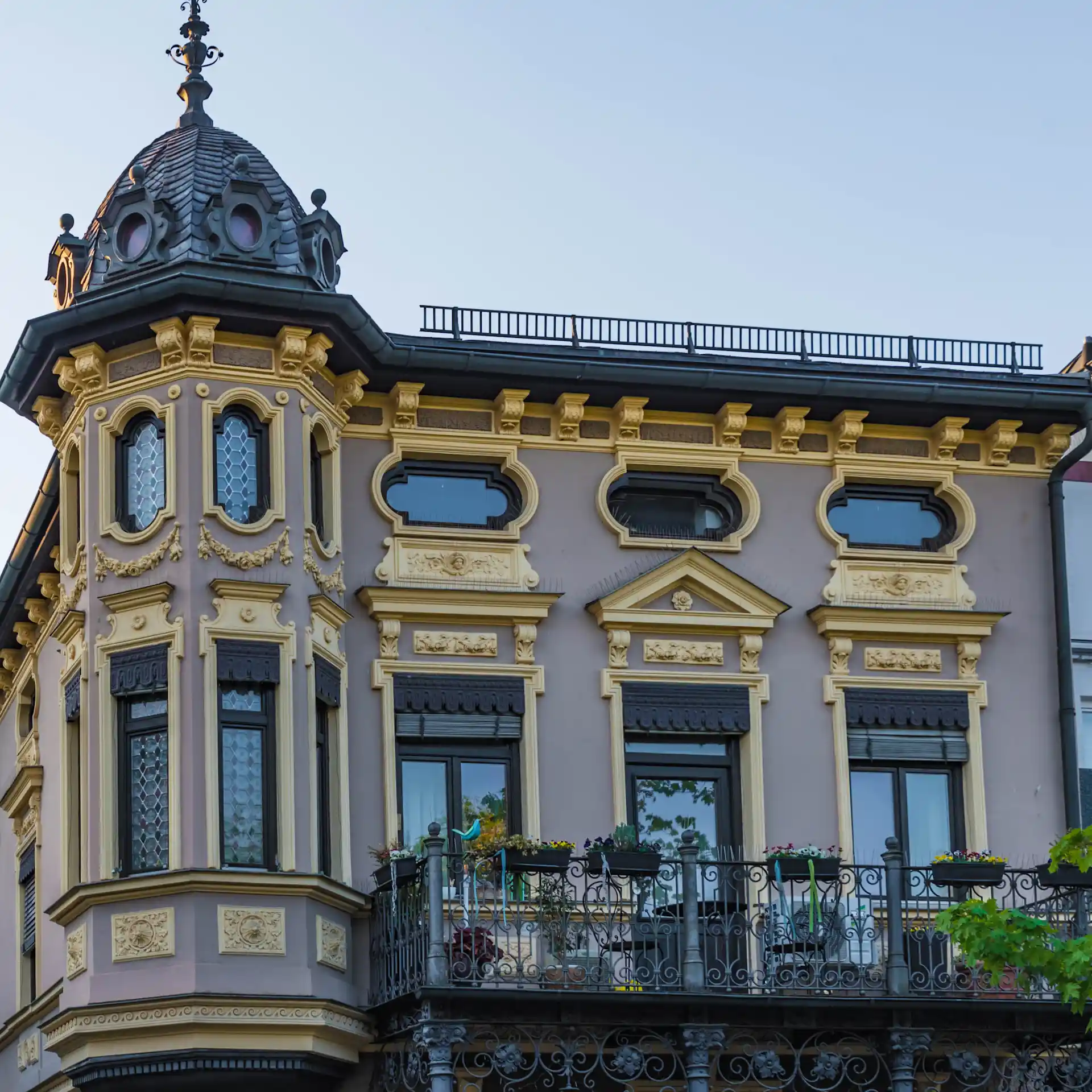 Historisches Wohnhaus mit reich verzierten Fassadendetails und Balkon, Ecke des Gebäudes mit Kuppel.