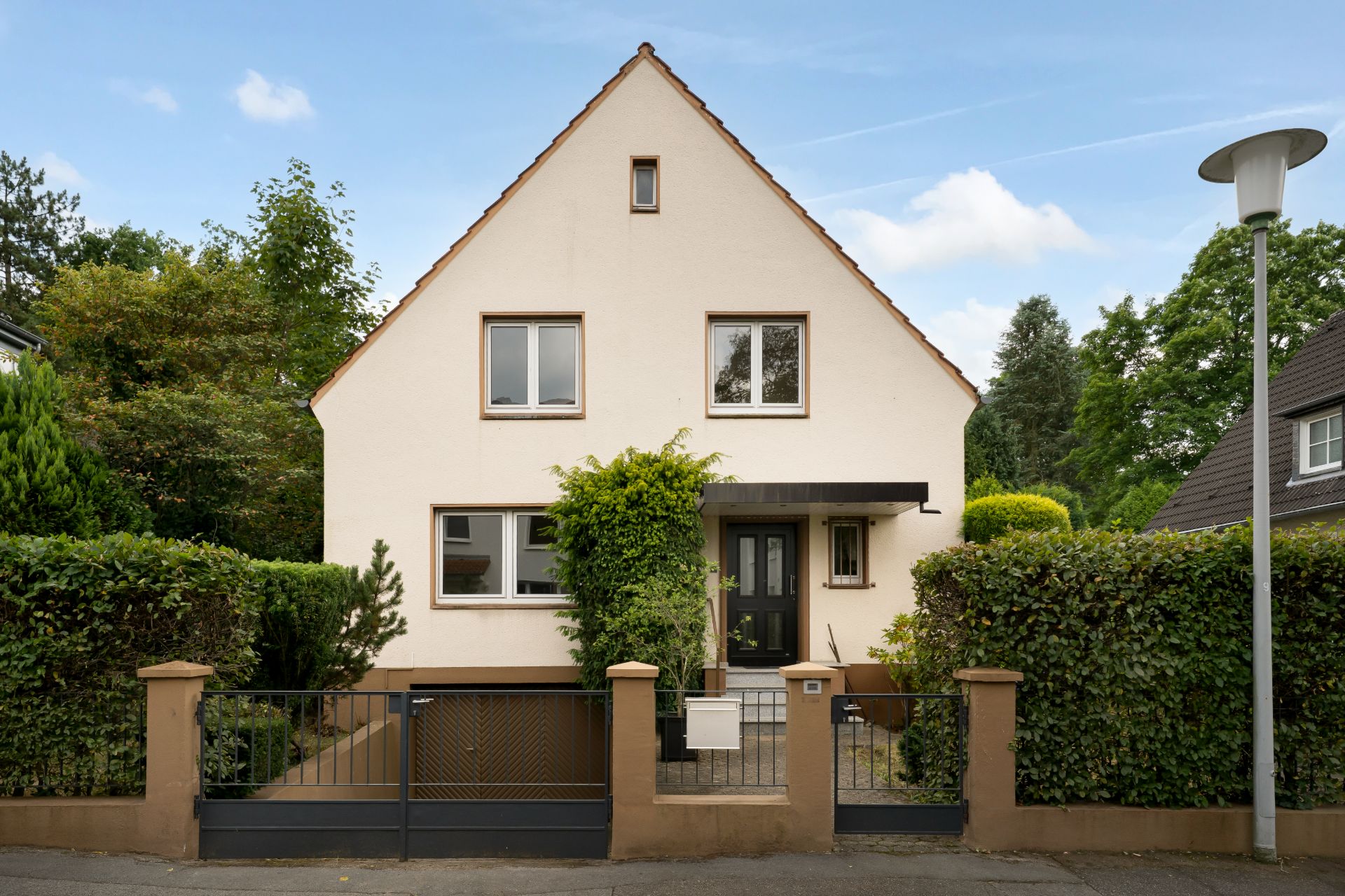 Vorderansicht eines Einfamilienhauses mit Garten und Zaun.