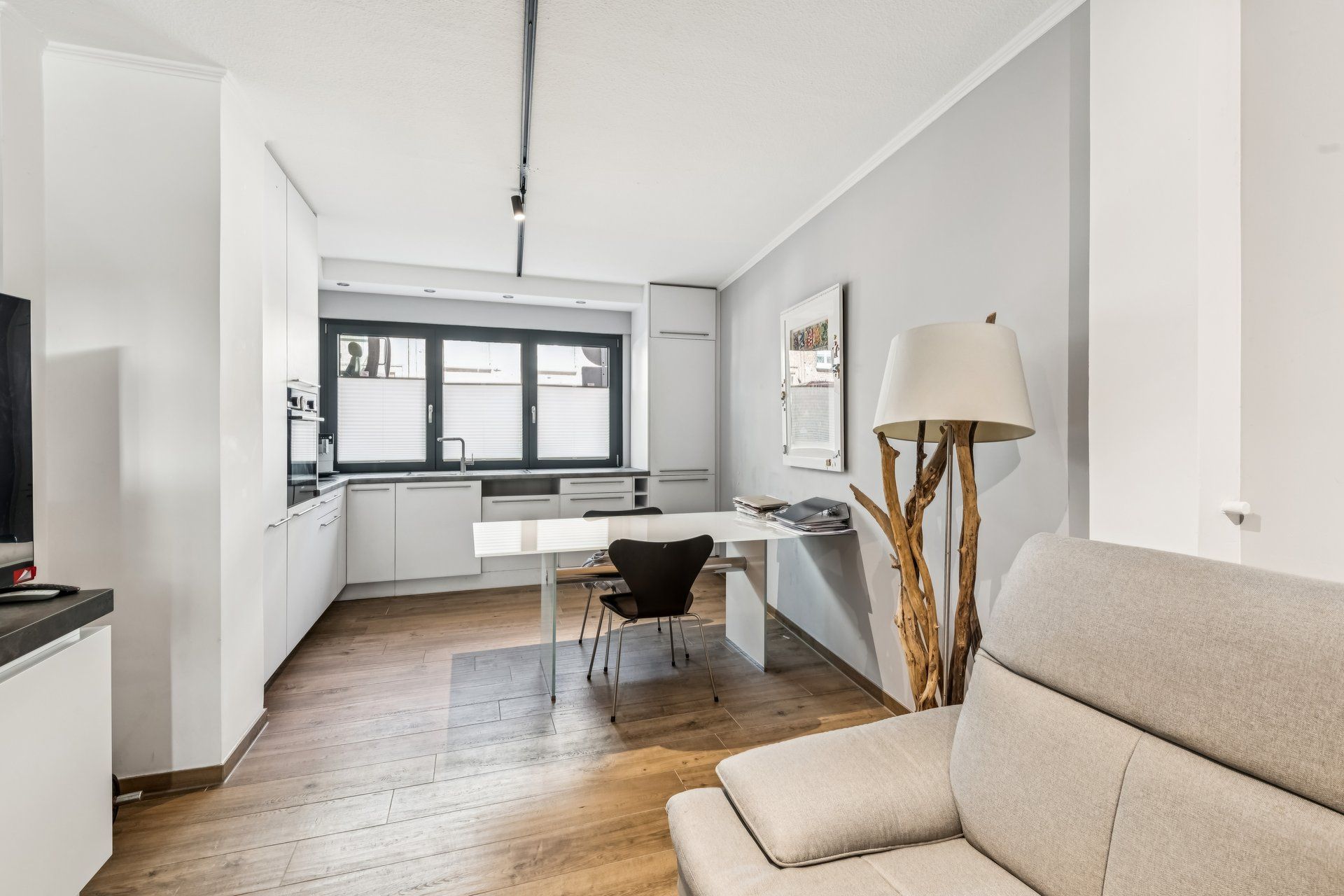 Moderne Küche mit Esstisch, Stuhl, Stehlampe und Sofa auf Holzfußboden.