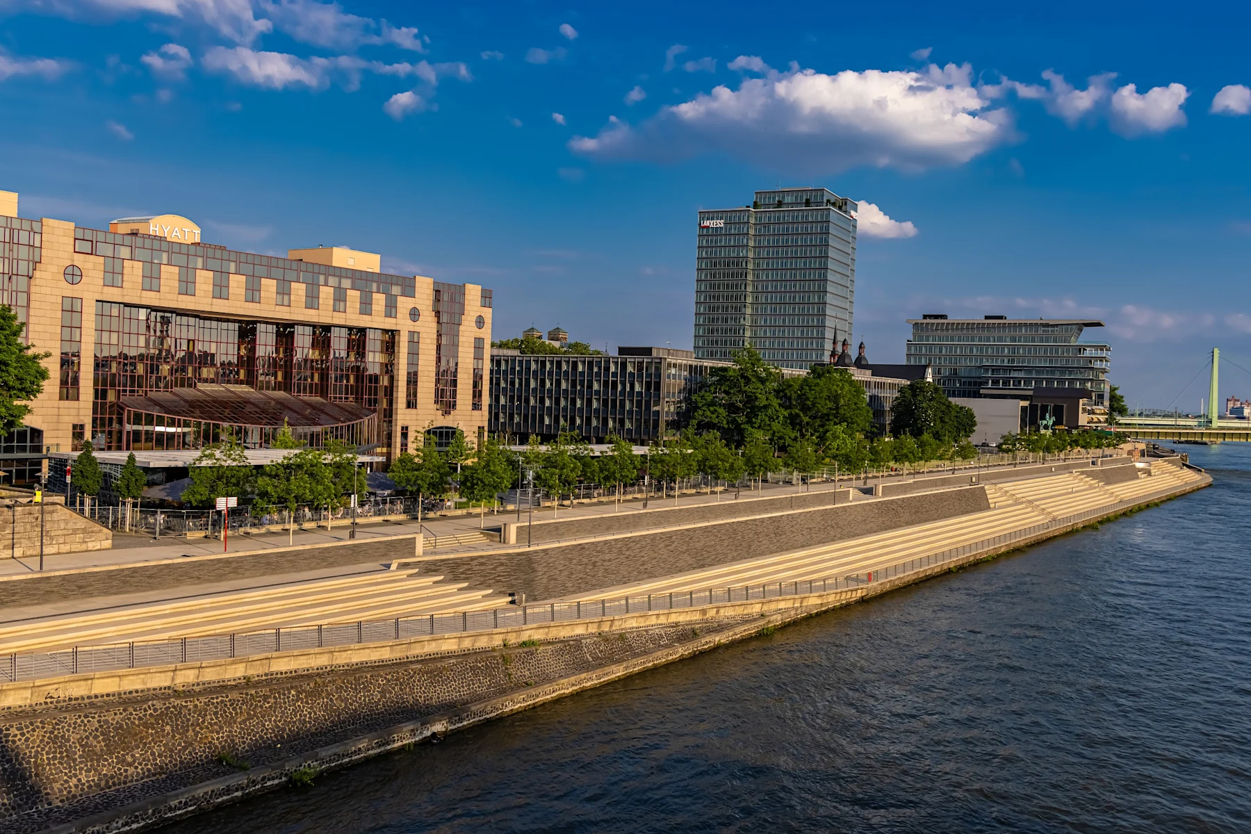 Moderne Gebäude und breite Treppen am Flussufer bei klarem Himmel.