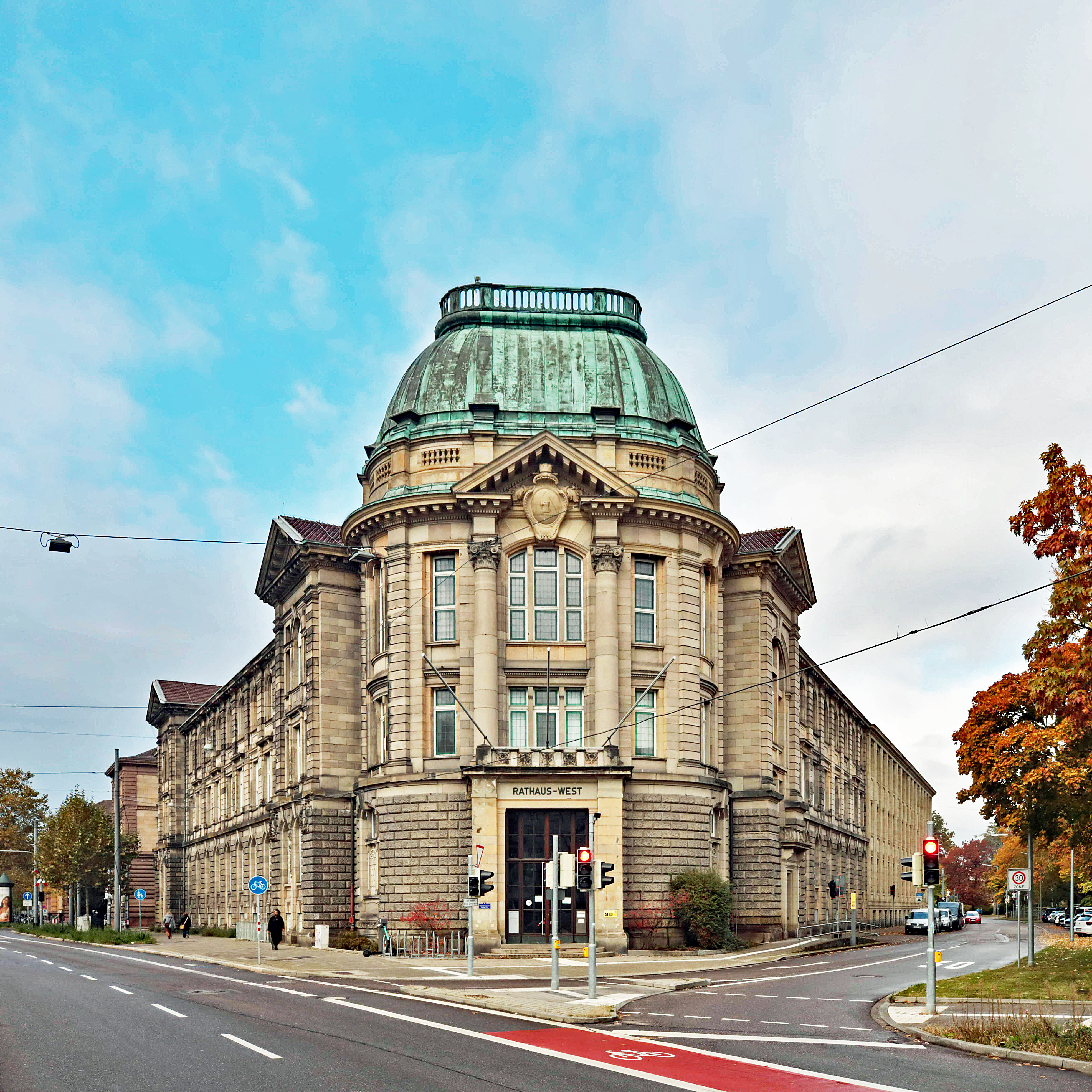 Gepflasterte Straße mit Bänken, Blumentöpfen und Wohnhäusern an beiden Seiten.